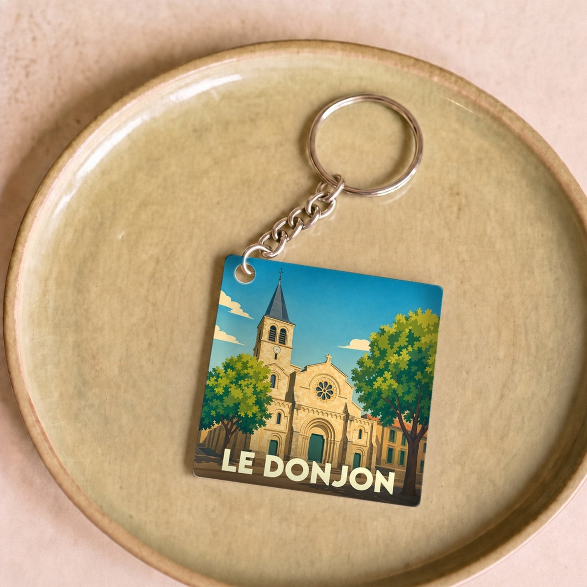 Porte-clés souvenir de la ville de Le Donjon avec une illustration stylisée de son église.