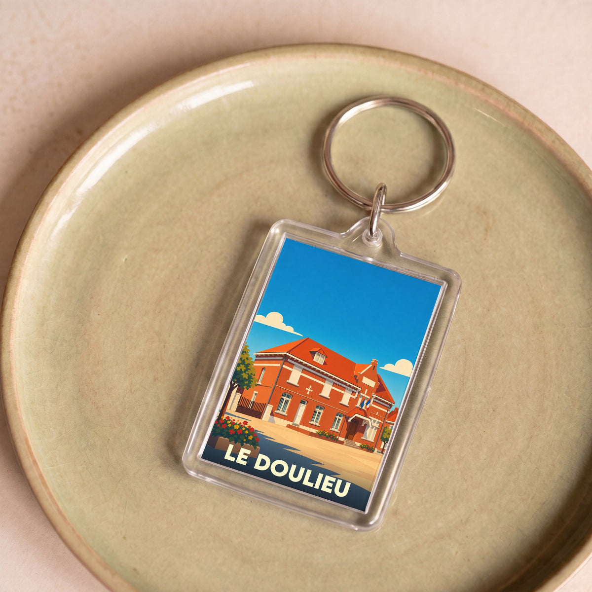 Porte-clés souvenir de la ville de Le Doulieu avec une illustration stylisée.