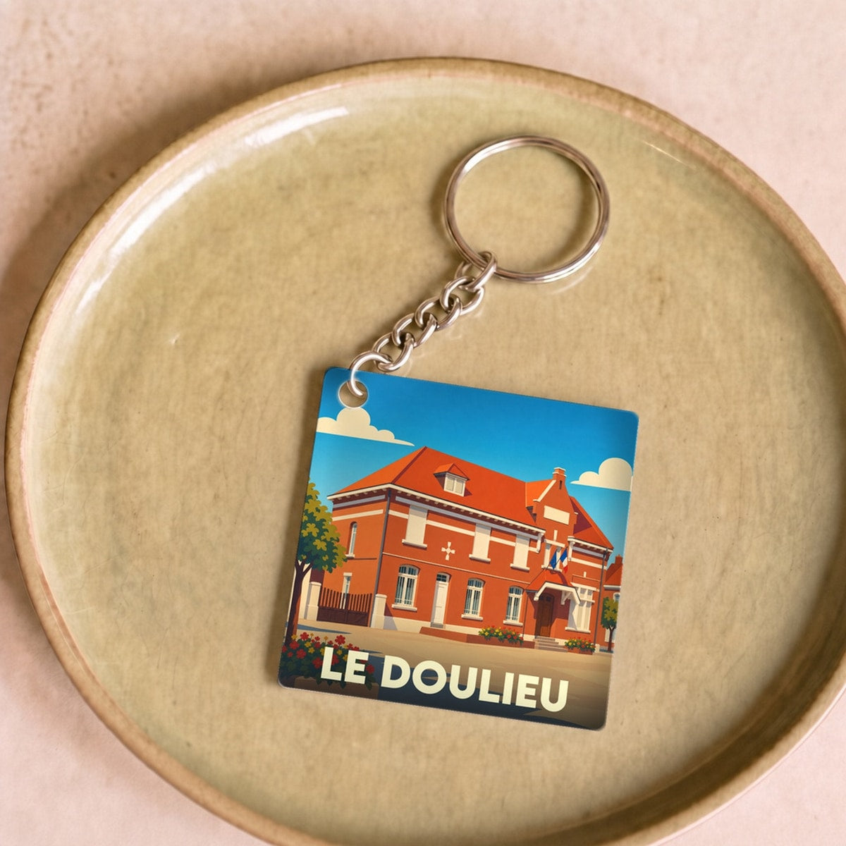 Porte-clés souvenir de la ville de Le Doulieu avec une illustration stylisée.