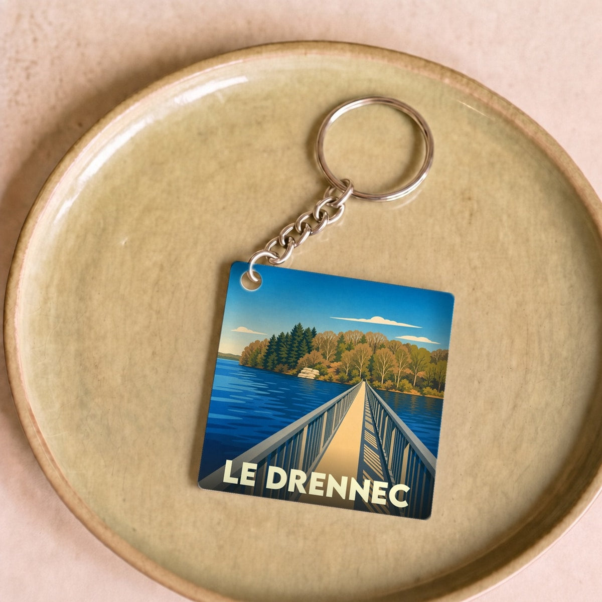 Porte-clés souvenir de la ville de Le Drennec avec une illustration stylisée d'un pont sur un lac.