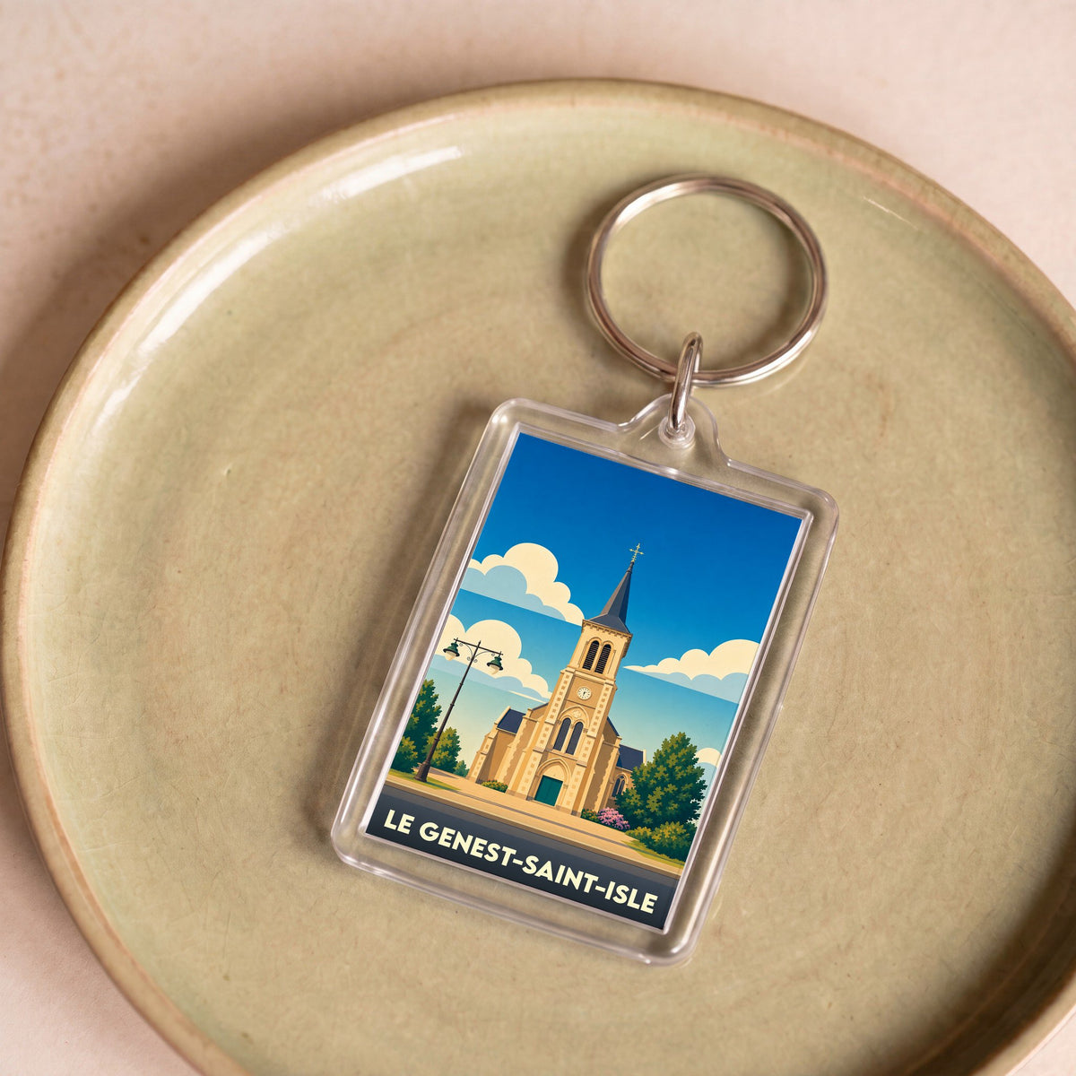 Porte-clés souvenir de la ville de Le Genest-Saint-Isle avec une illustration stylisée de son église.