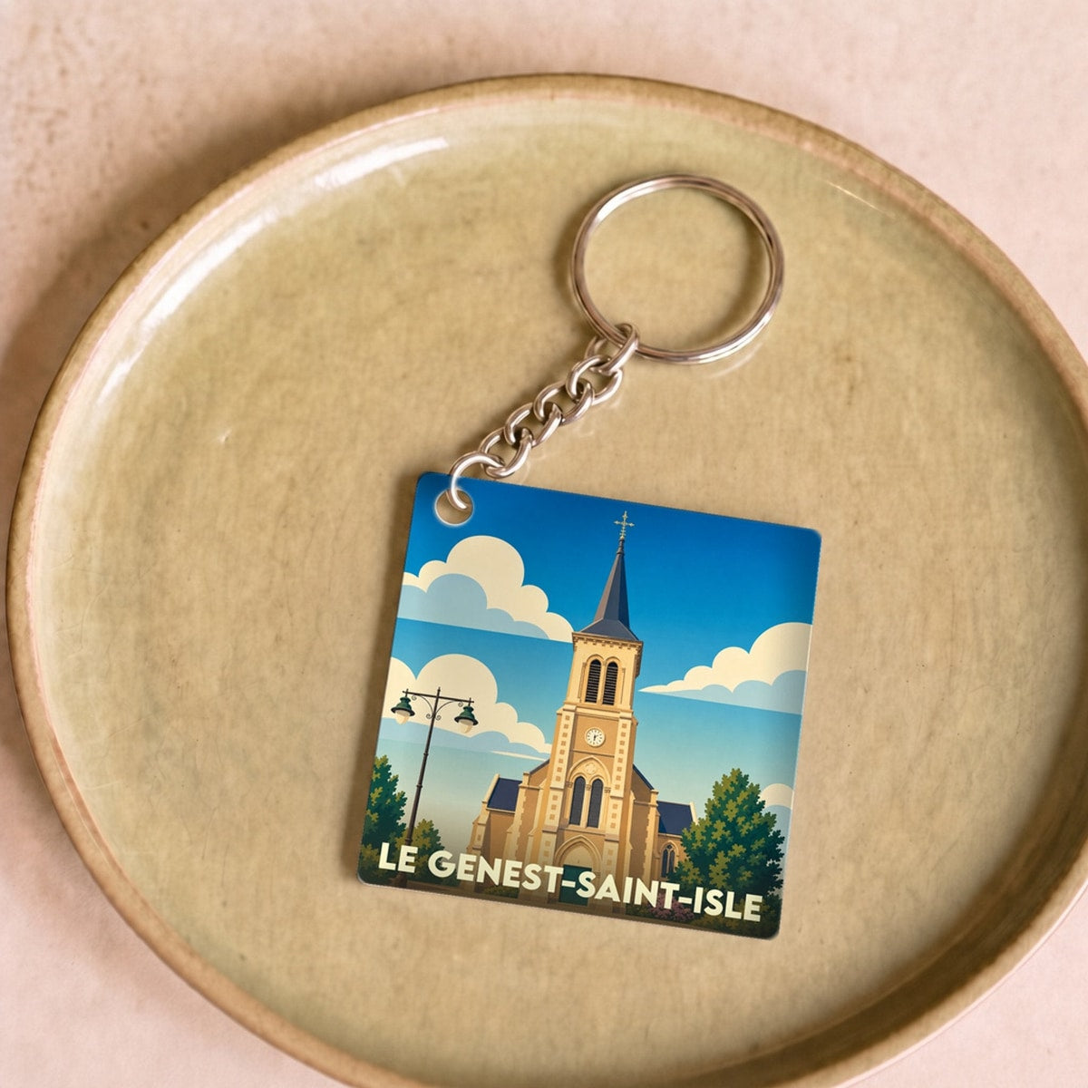 Porte-clés souvenir de la ville de Le Genest-Saint-Isle avec une illustration stylisée de son église.