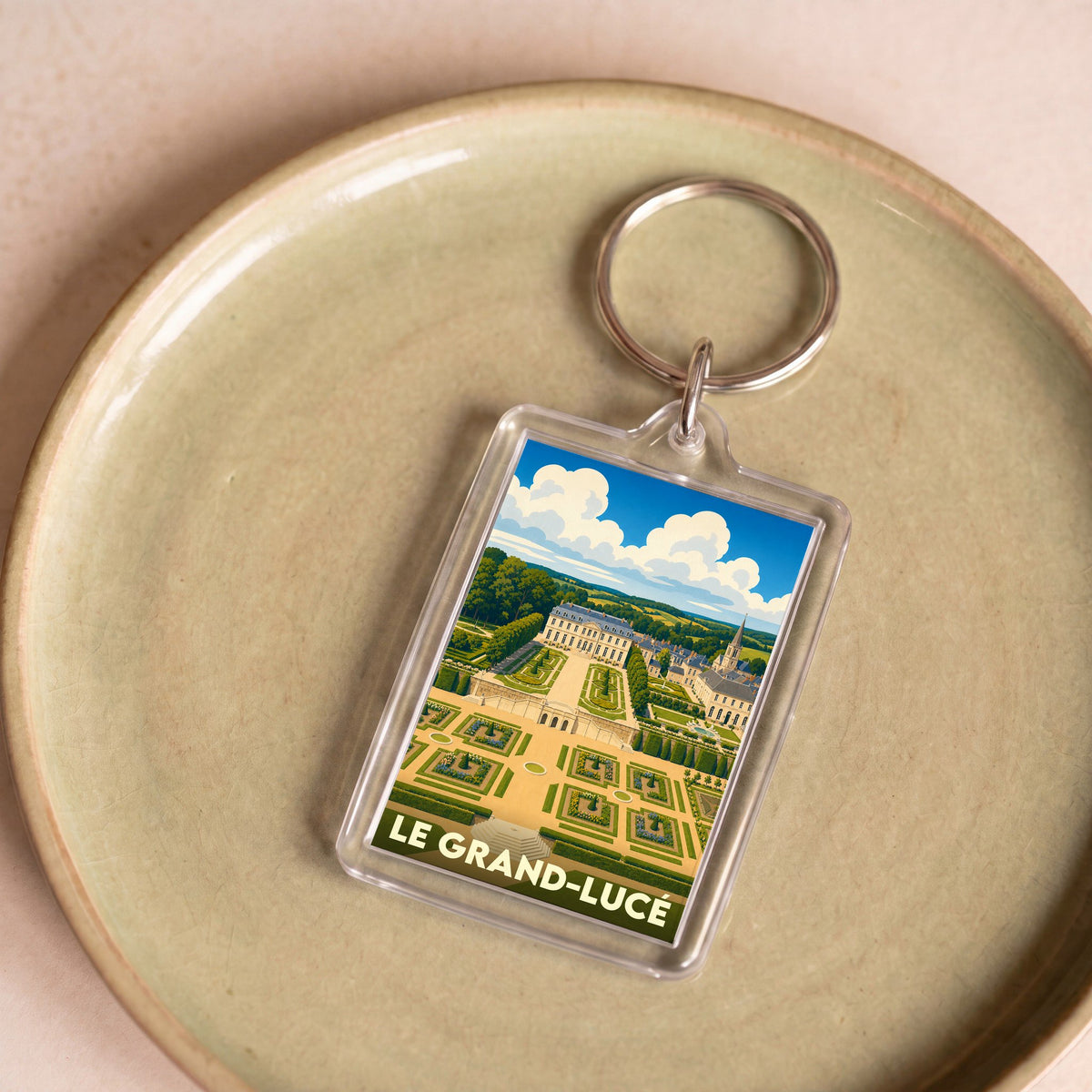 Porte-clés souvenir de la ville de Le Grand-Lucé avec une illustration stylisée de son château et de ses jardins.