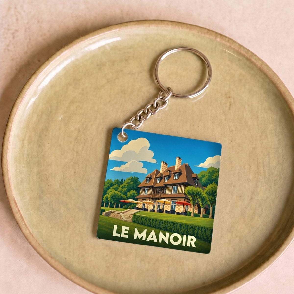 Porte-clés souvenir de la ville de Le Manoir avec une illustration stylisée.