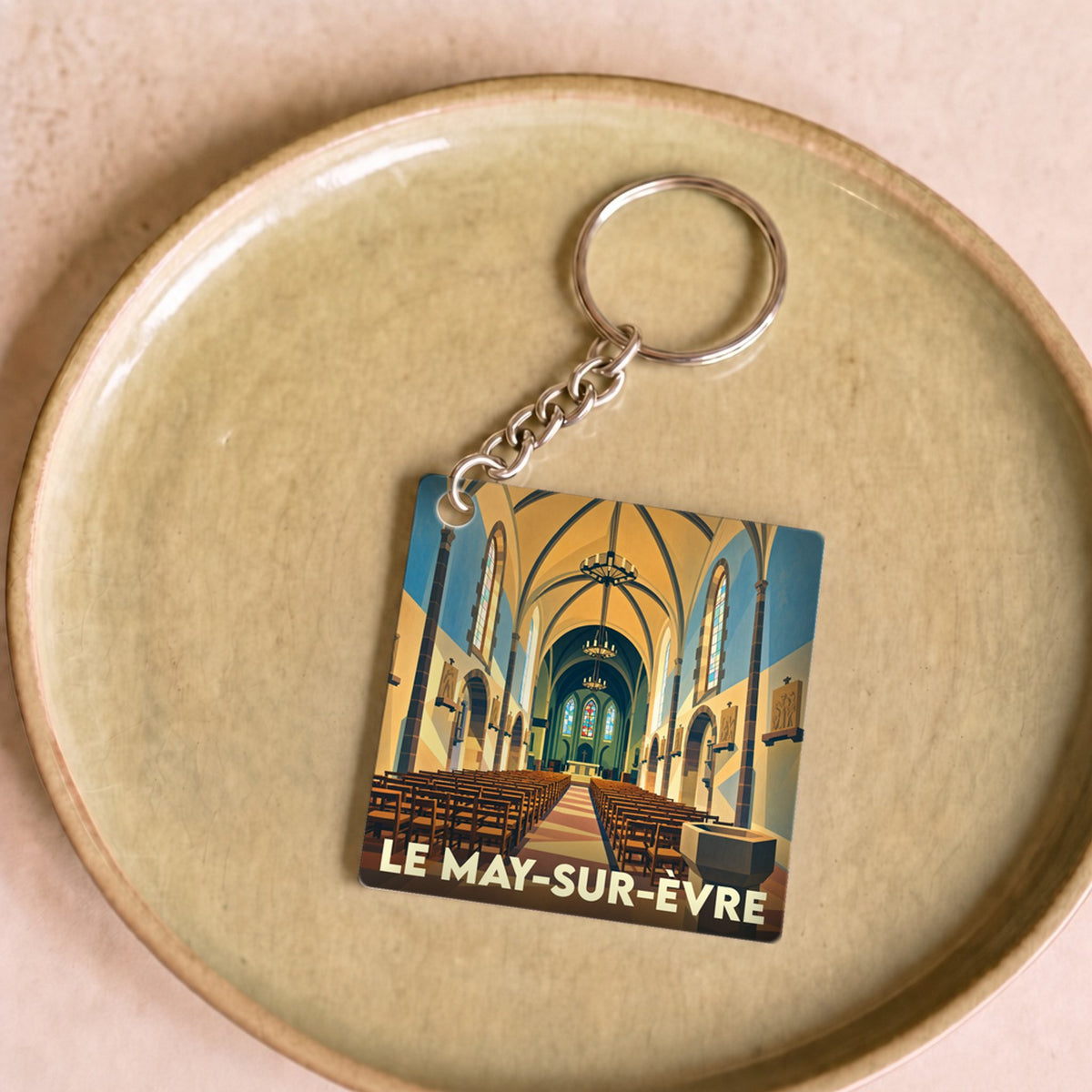 Porte-clés souvenir de la ville de Le May-sur-Èvre avec une illustration stylisée de l'intérieur de son église.