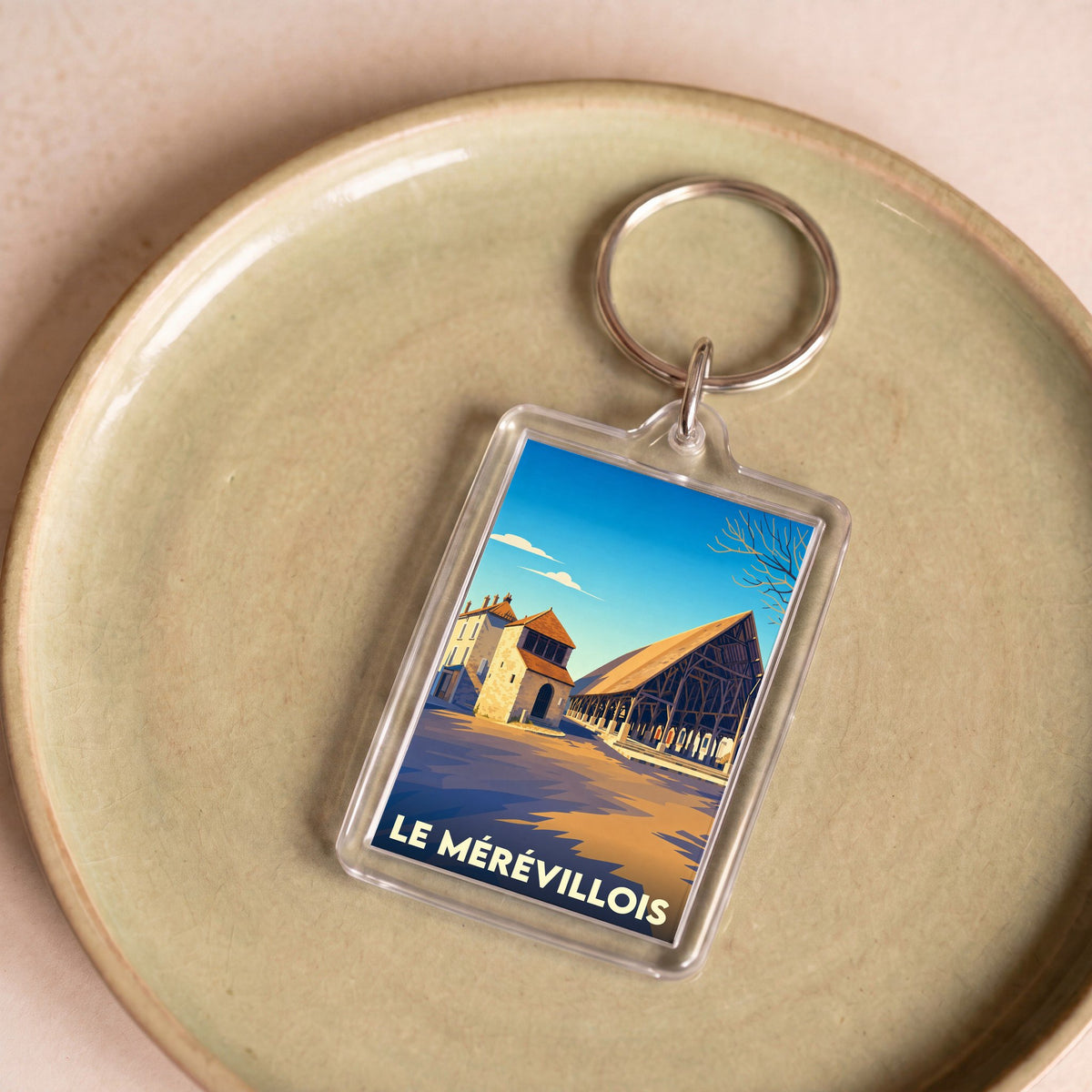 Porte-clés souvenir de la ville du Mérévillois avec une illustration stylisée de ses halles historiques.