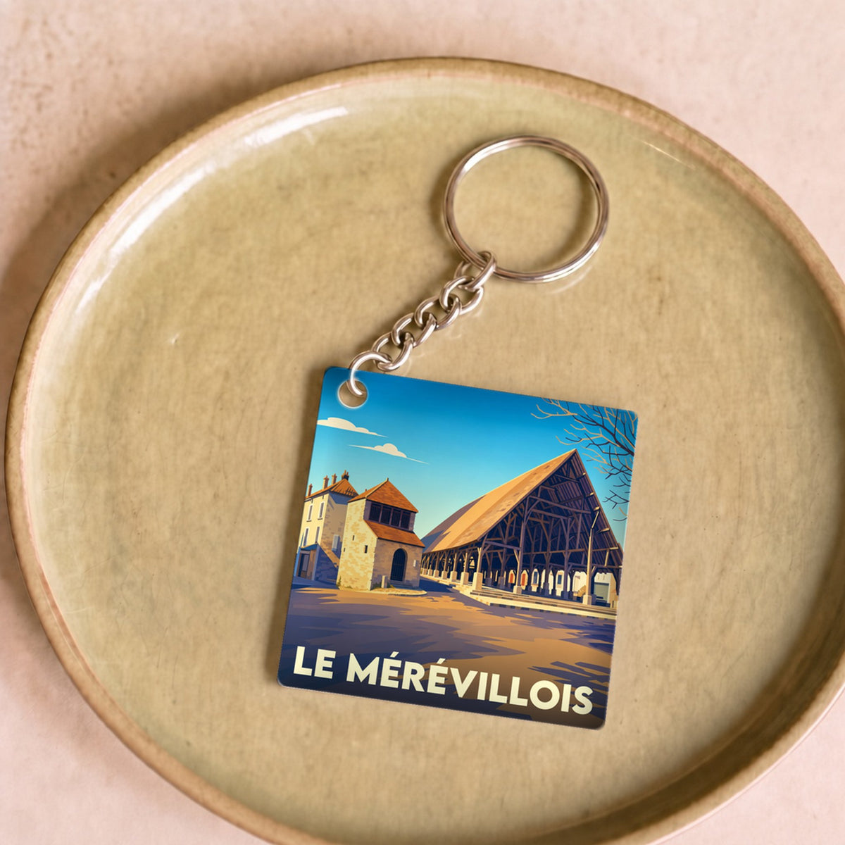 Porte-clés souvenir de la ville du Mérévillois avec une illustration stylisée de ses halles historiques.