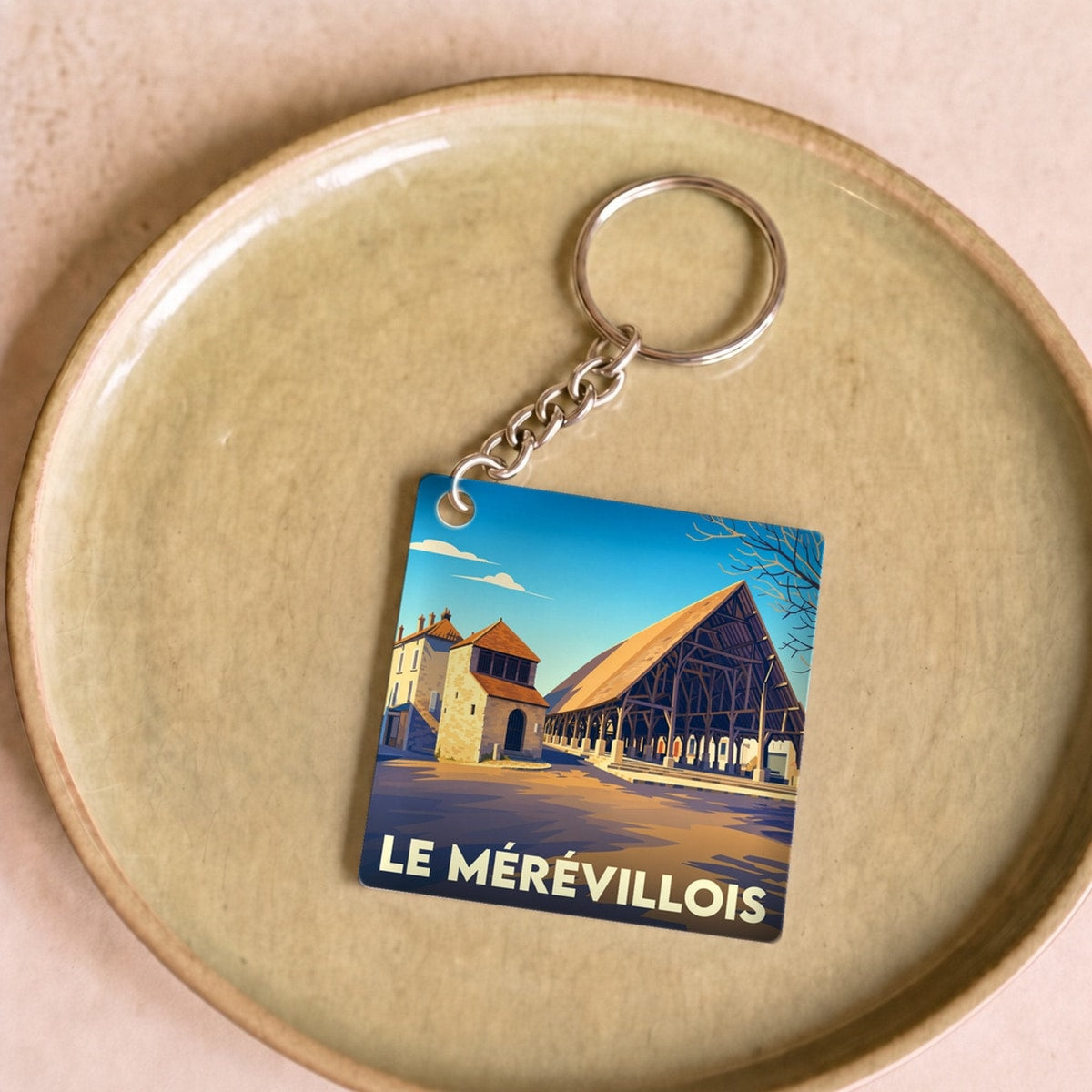Porte-clés souvenir de la ville du Mérévillois avec une illustration stylisée de ses halles historiques.
