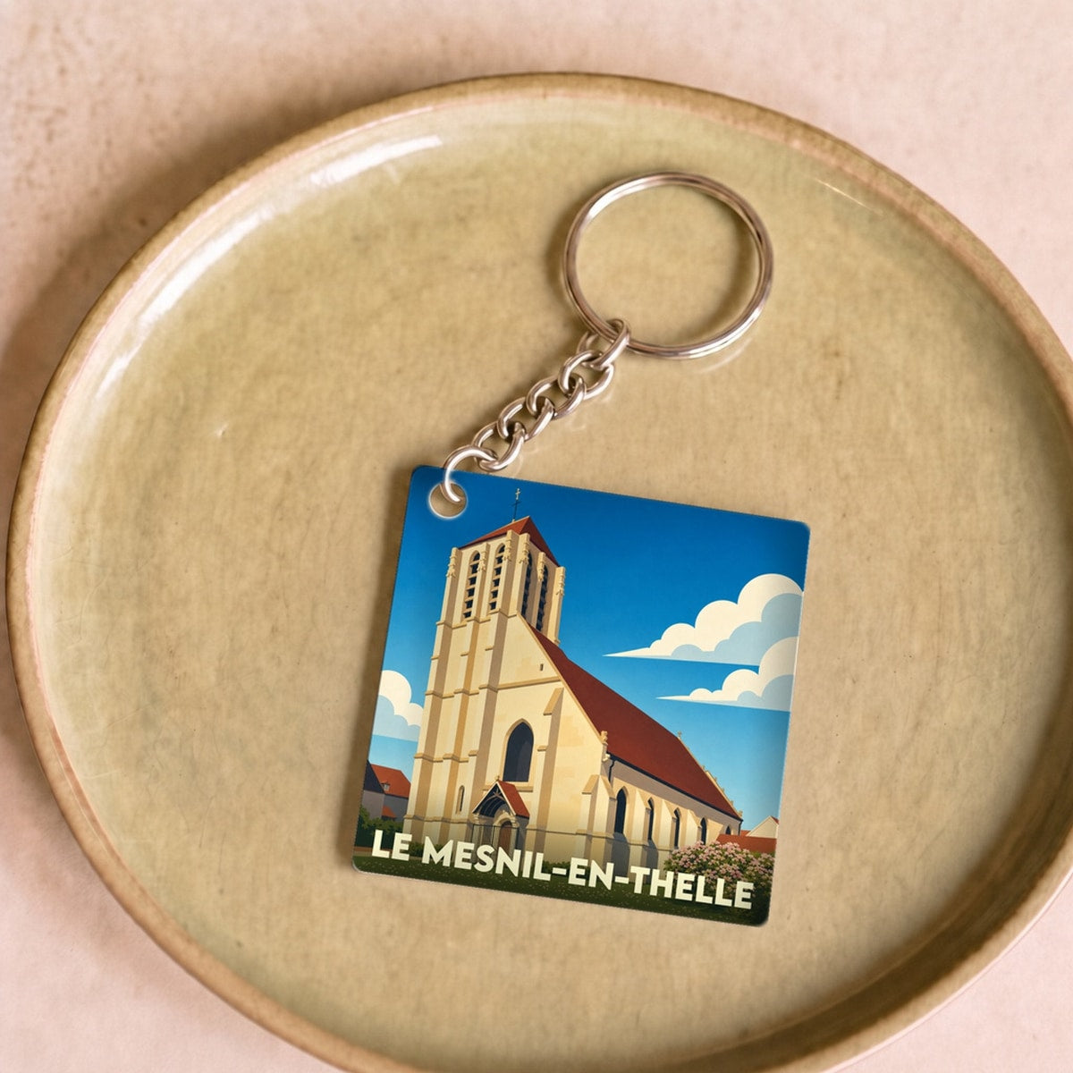Porte-clés souvenir de la ville du Mesnil-en-Thelle avec une illustration stylisée de son église.
