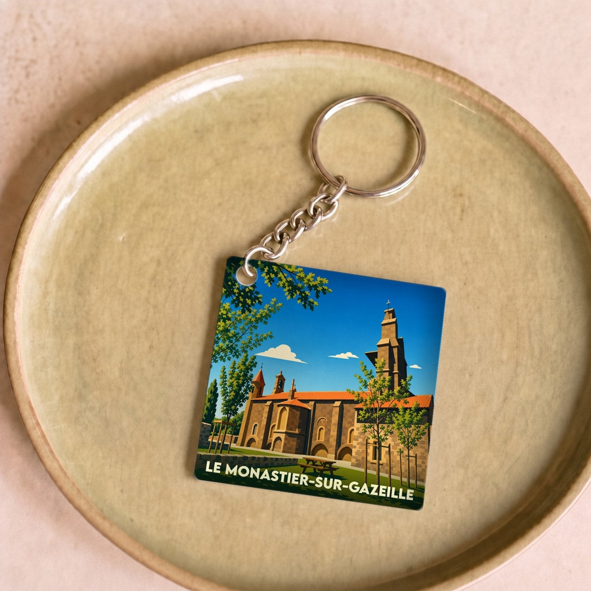Porte-clés souvenir de la ville de Le Monastier-sur-Gazeille avec une illustration stylisée de son église.