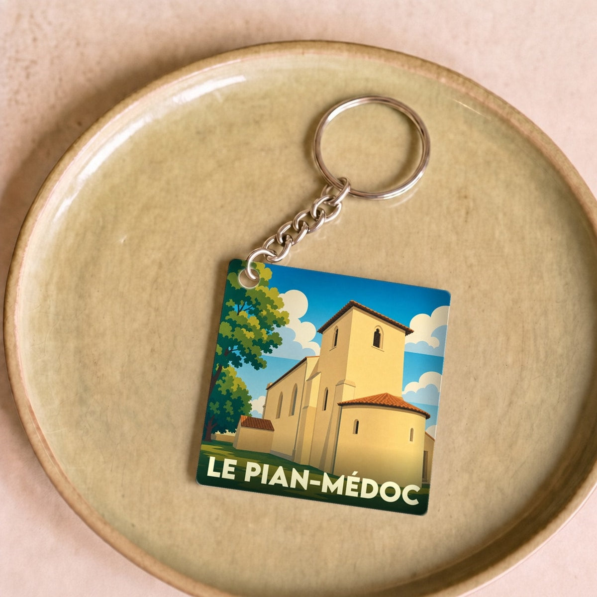Porte-clés souvenir de la ville de Le Pian-Médoc avec une illustration stylisée de son église.