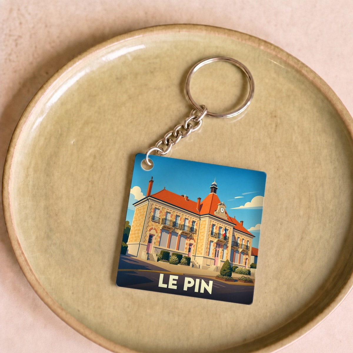 Porte-clés souvenir de la ville de Le Pin avec une illustration stylisée de sa mairie.