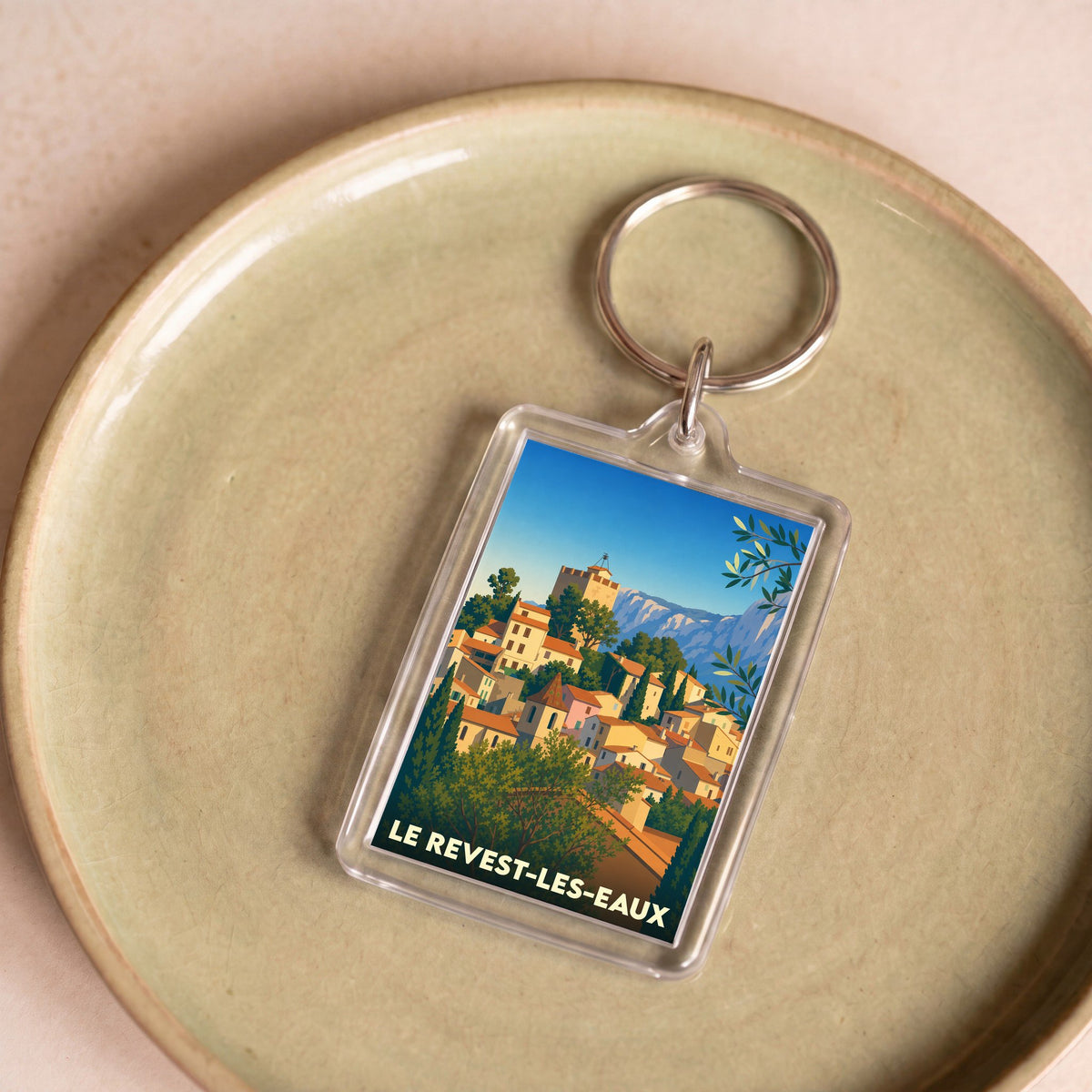 Porte-clés souvenir de la ville de Le Revest-les-Eaux avec une illustration stylisée.