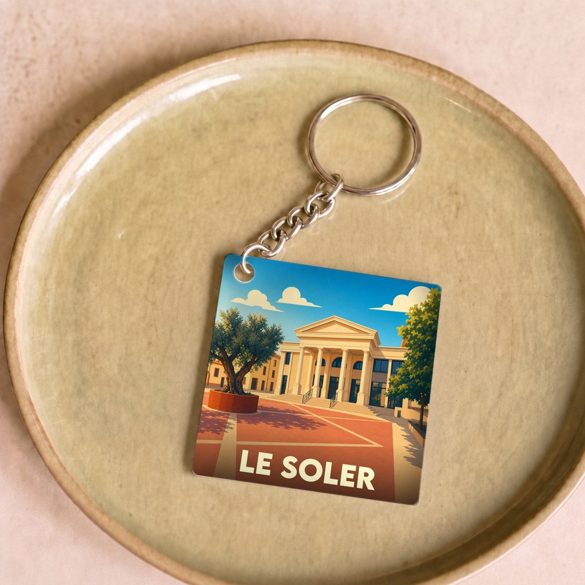 Porte-clés souvenir de la ville de Le Soler avec une illustration stylisée.