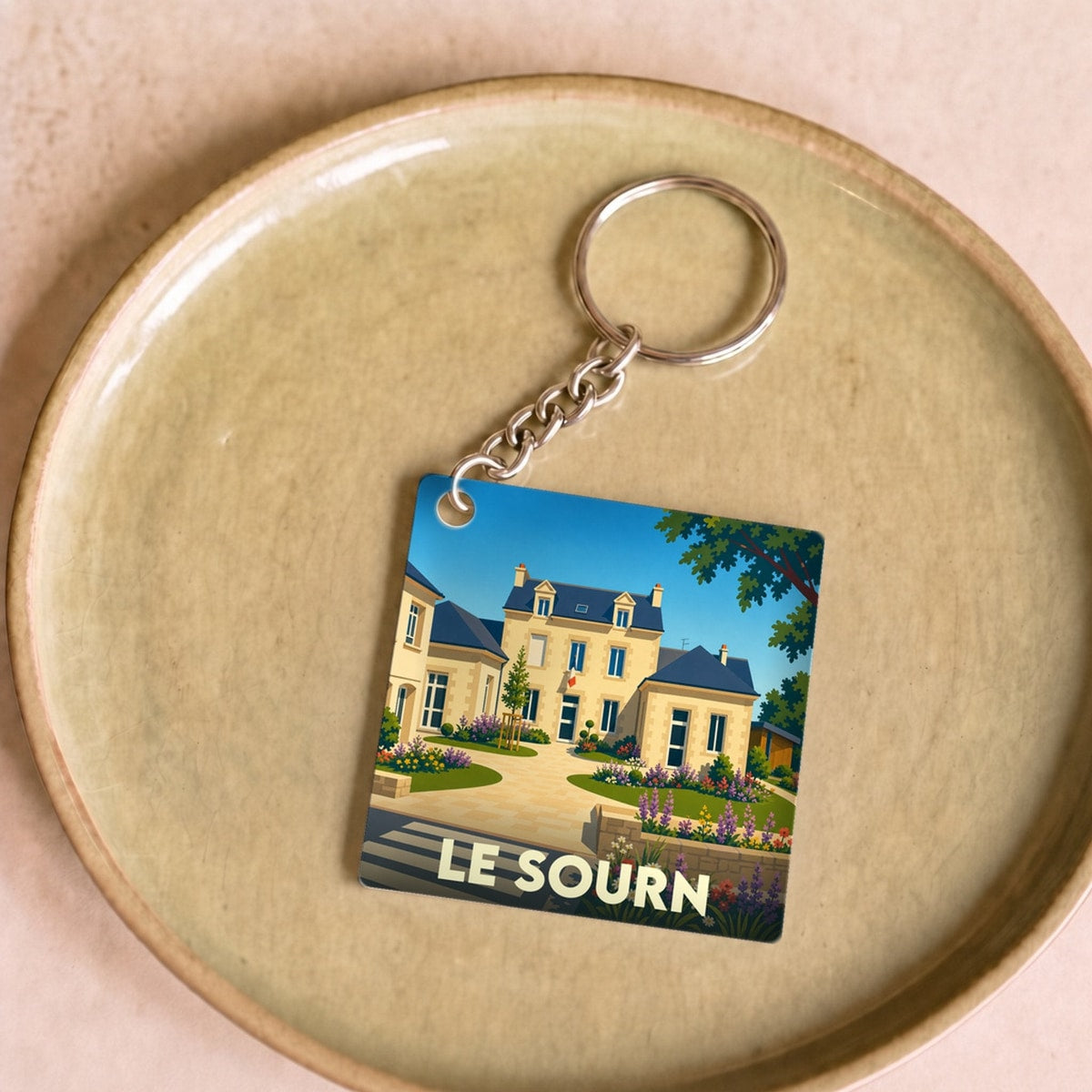 Porte-clés souvenir de la ville de Le Sourn avec une illustration stylisée.