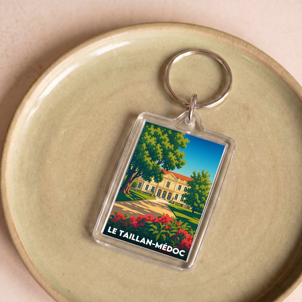 Porte-clés souvenir de la ville de Le Taillan-Médoc avec une illustration stylisée d'un château.