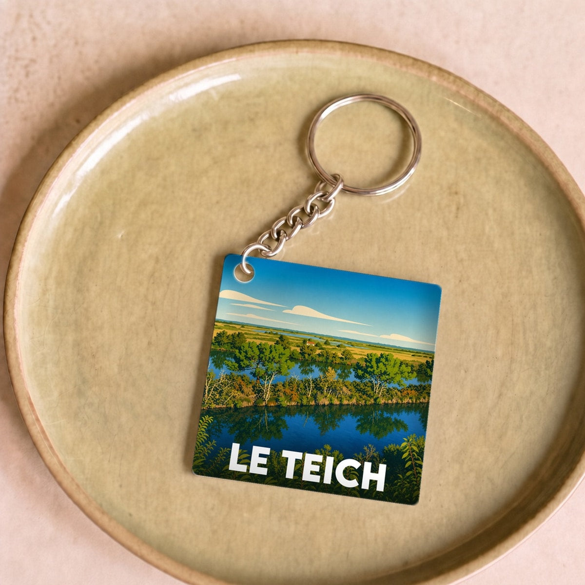 Porte-clés souvenir de la ville de Le Teich avec une illustration paysagère stylisée.