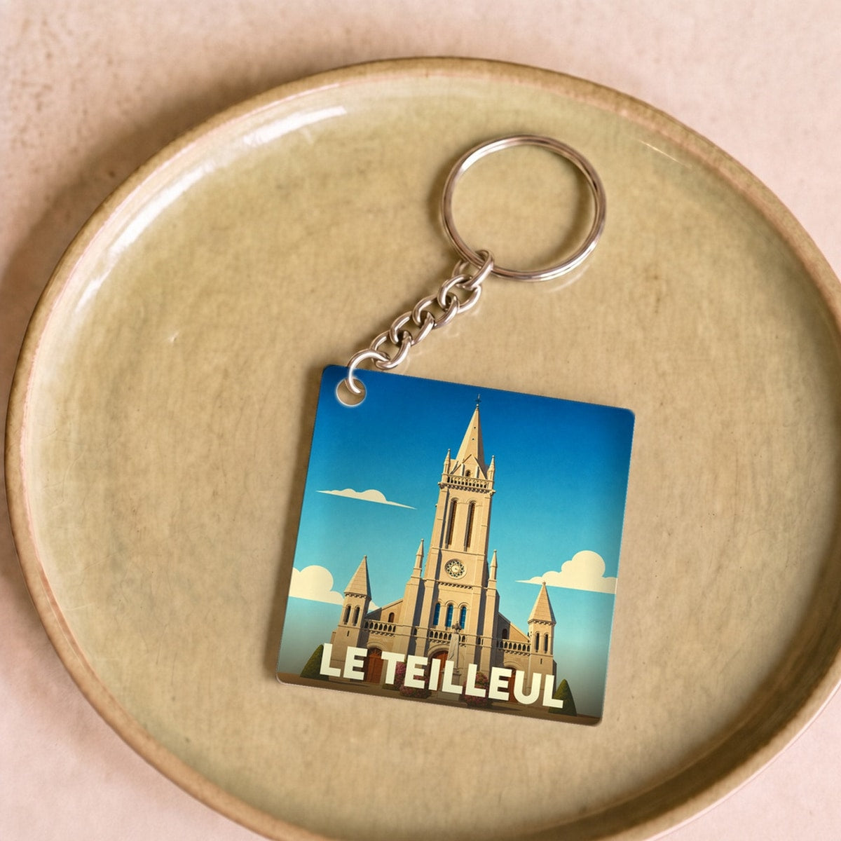 Porte-clés souvenir de la ville de Le Teilleul avec une illustration stylisée de son église.