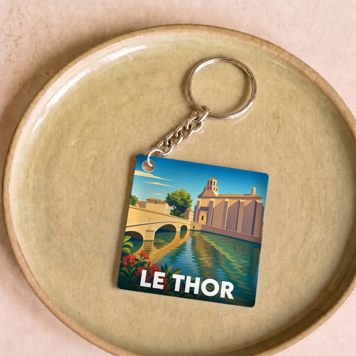 Porte-clés souvenir de la ville du Thor avec une illustration stylisée d'un pont et d'une église.