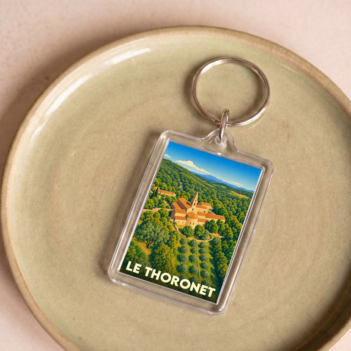 Porte-clés souvenir de la ville du Thoronet avec une illustration stylisée d'une abbaye entourée de verdure.