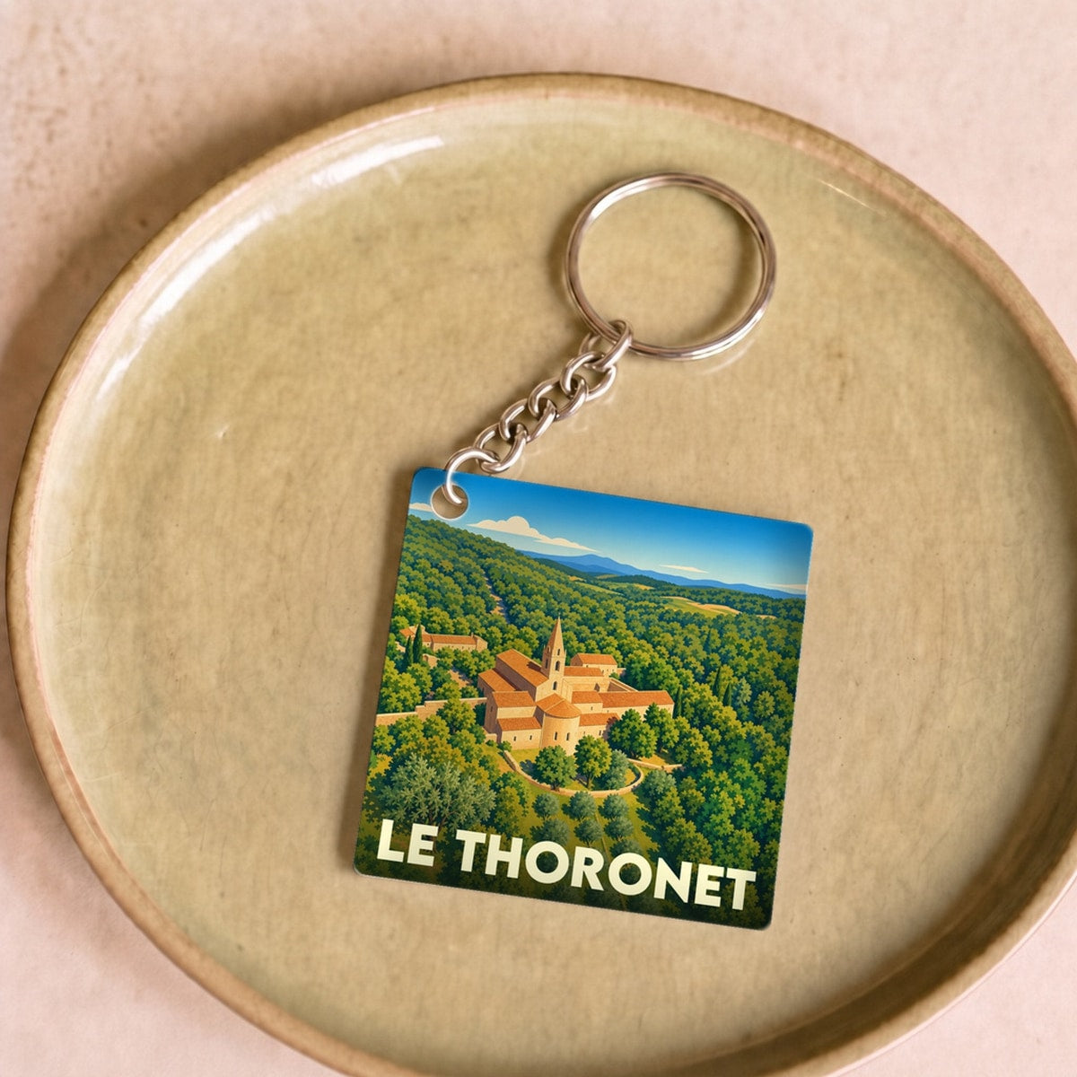Porte-clés souvenir de la ville du Thoronet avec une illustration stylisée d'une abbaye entourée de verdure.