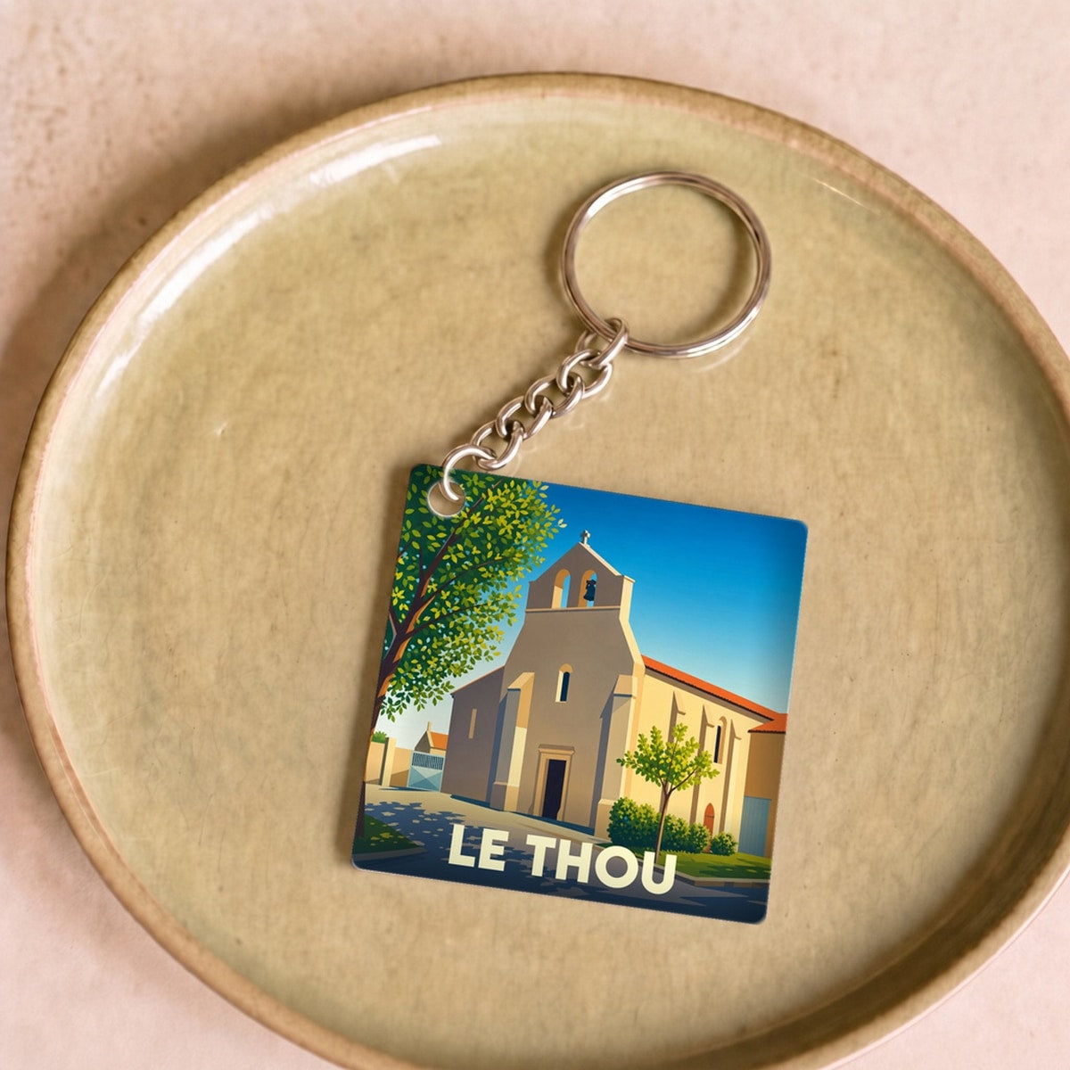 Porte-clés souvenir de la ville de Le Thou avec une illustration stylisée de son église.