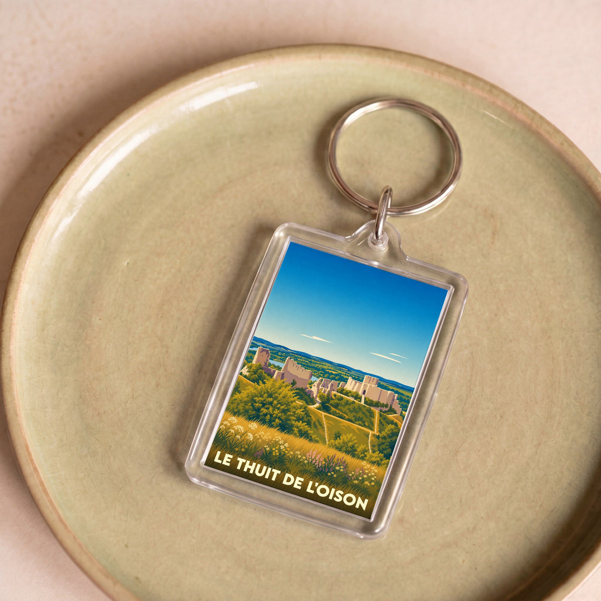 Porte-clés souvenir de la ville de Le Thuit de l'Oison avec une illustration stylisée d'un paysage historique.