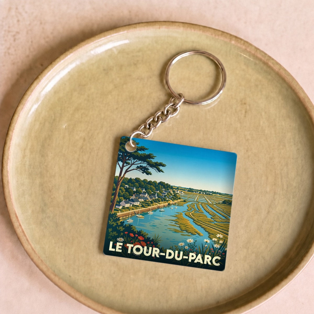 Porte-clés souvenir de la ville de Le Tour-du-Parc avec une illustration stylisée d'un paysage côtier.