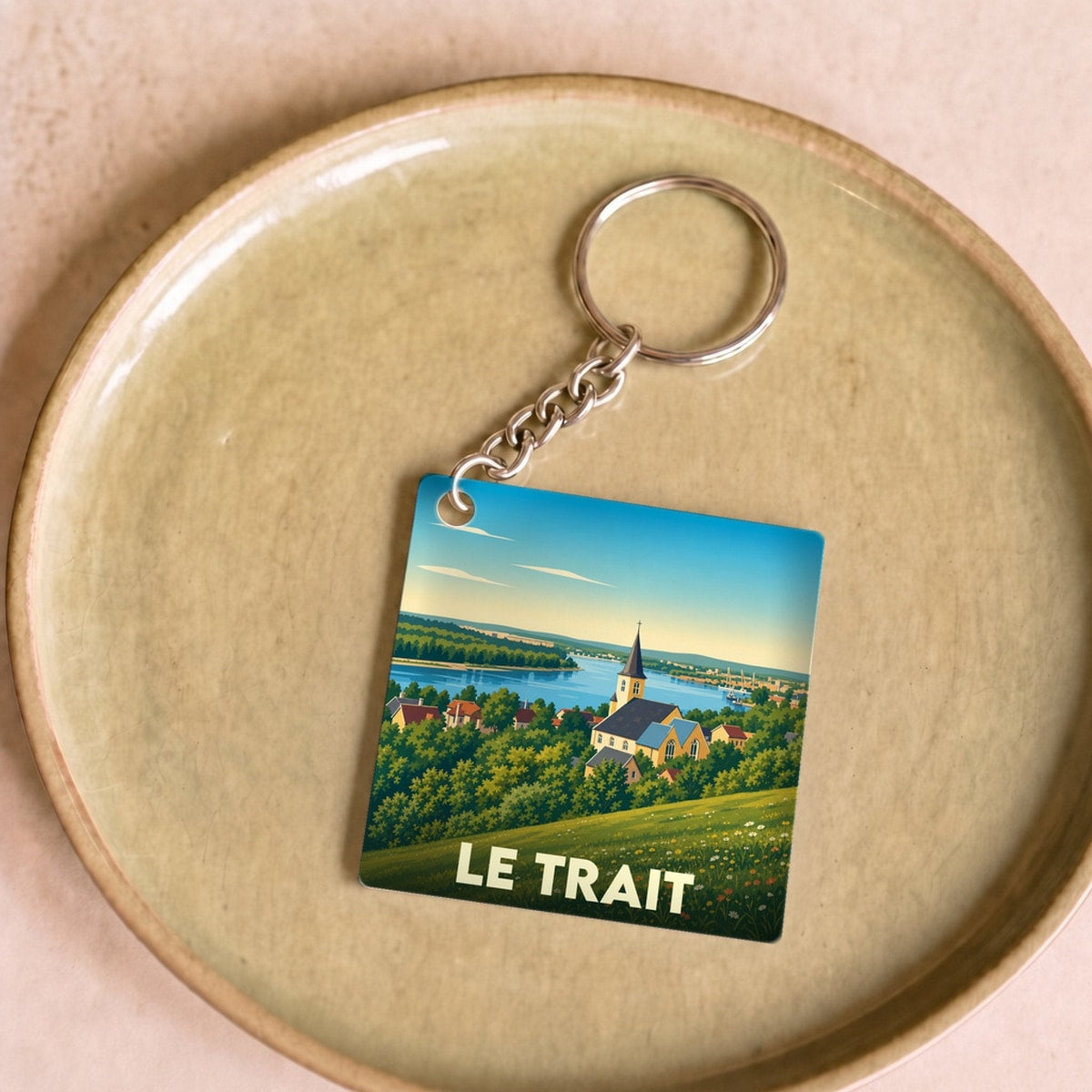 Porte-clés souvenir de la ville du Trait avec une illustration stylisée d'un paysage normand.