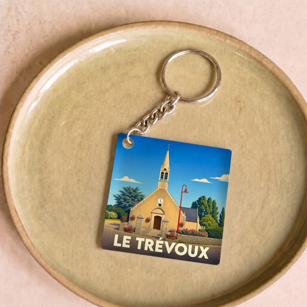 Porte-clés souvenir de la ville de Le Trévoux avec une illustration stylisée de son église.