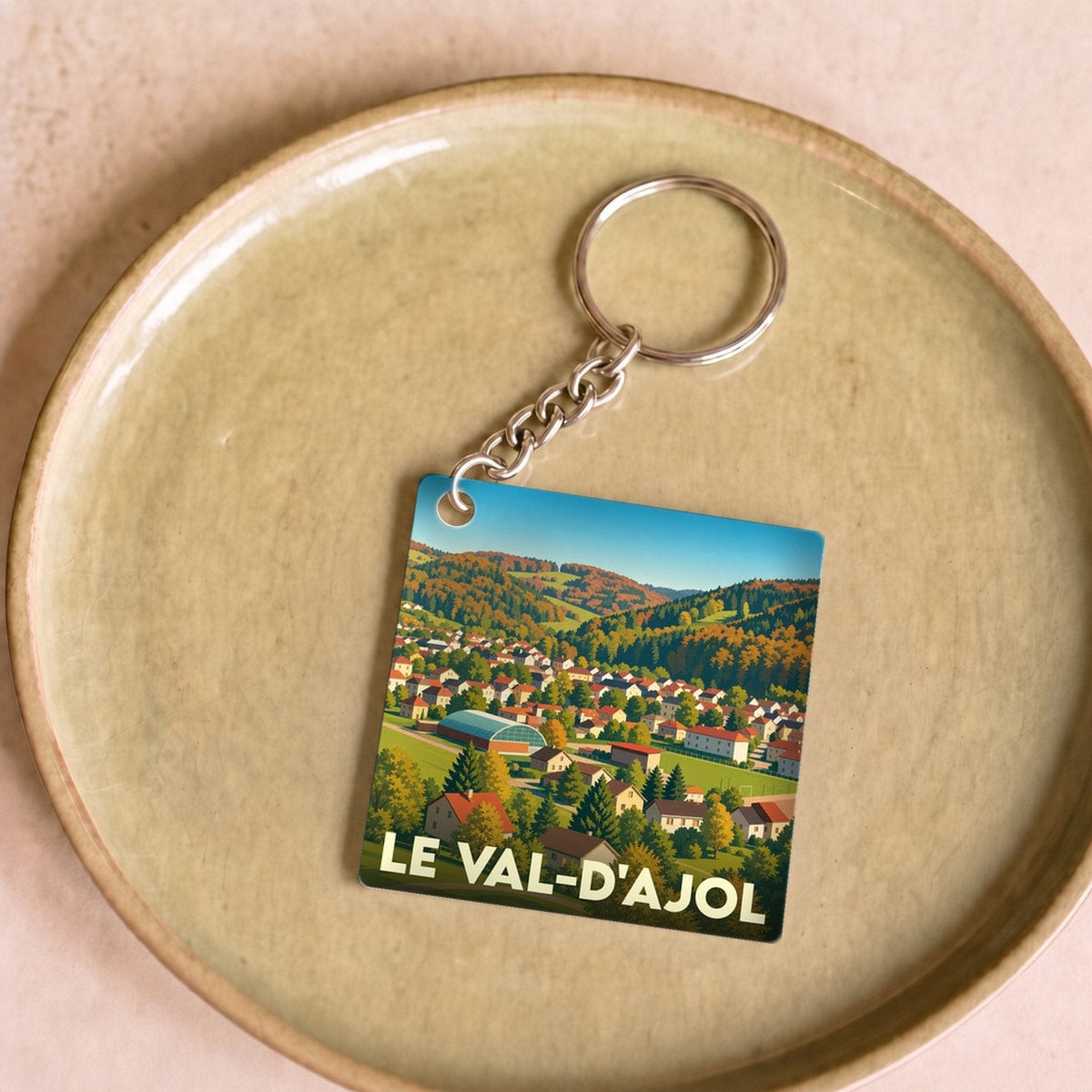 Porte-clés souvenir de la ville du Val-d'Ajol avec une illustration stylisée de ses paysages verdoyants.