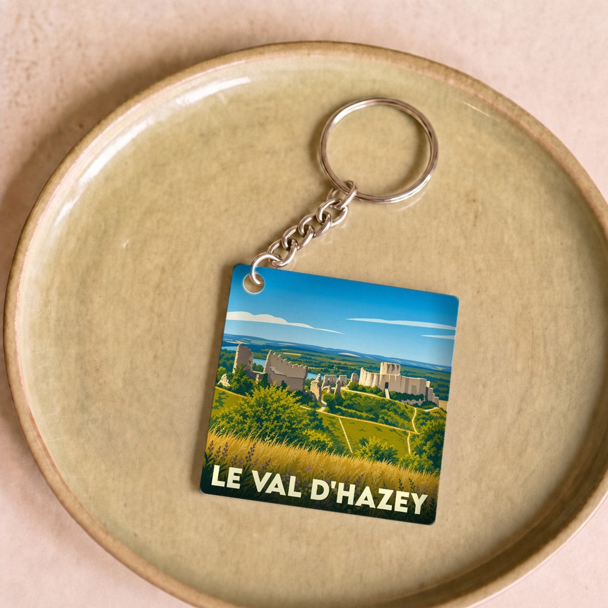 Porte-clés souvenir de la ville de Le Val d'Hazey avec une illustration stylisée d'un paysage historique.