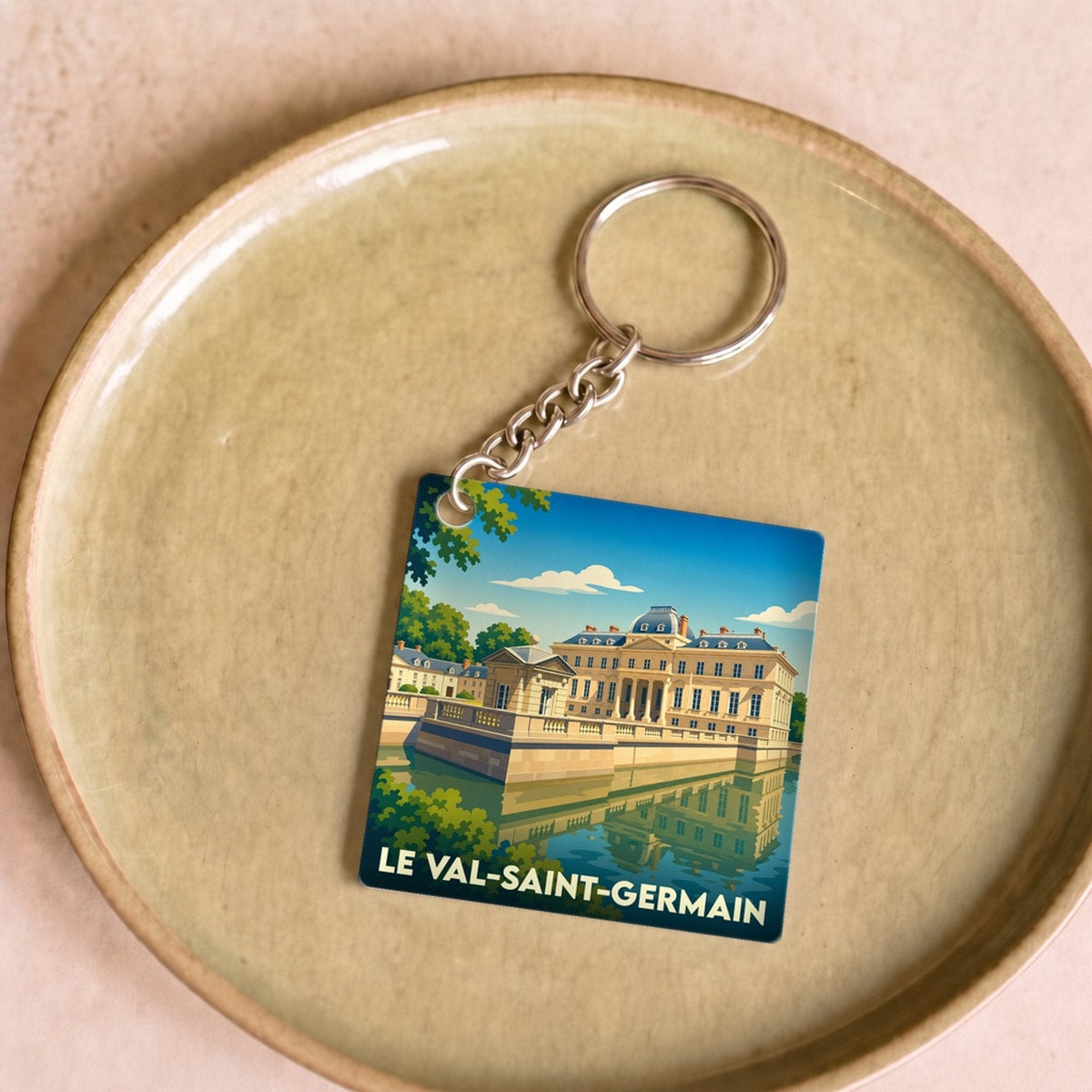 Porte-clés souvenir de la ville de Le Val-Saint-Germain avec une illustration stylisée d'un château se reflétant dans l'eau.