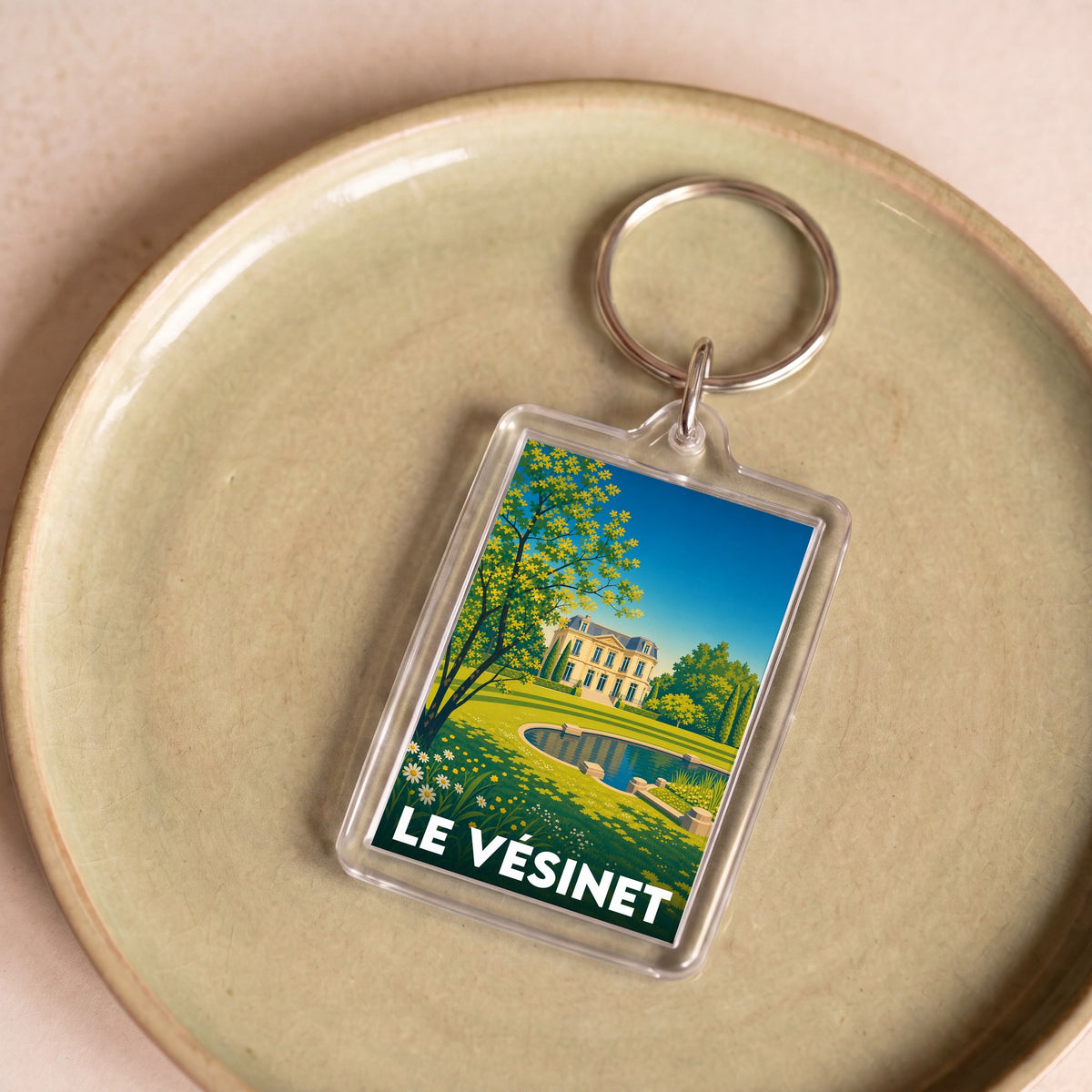 Porte-clés souvenir de la ville de Le Vésinet avec une illustration paysagère stylisée.