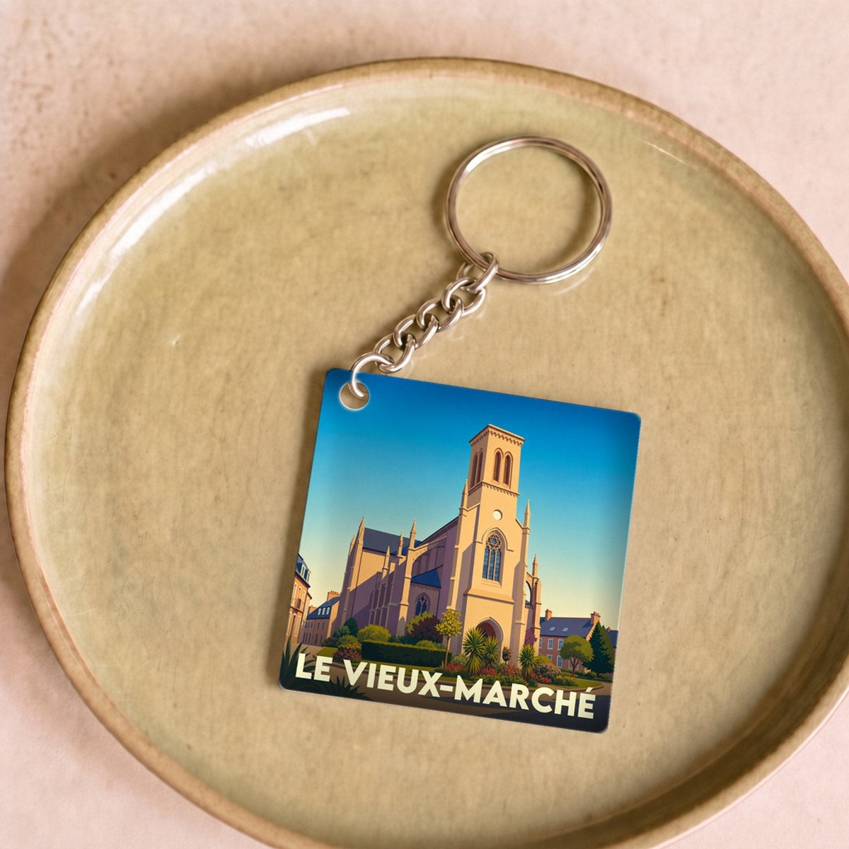 Porte-clés souvenir de la ville de Le Vieux-Marché avec une illustration stylisée de son église.