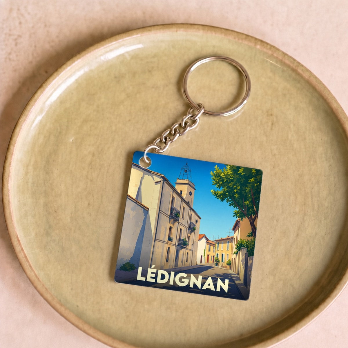 Porte-clés souvenir de la ville de Lédignan avec une illustration stylisée.