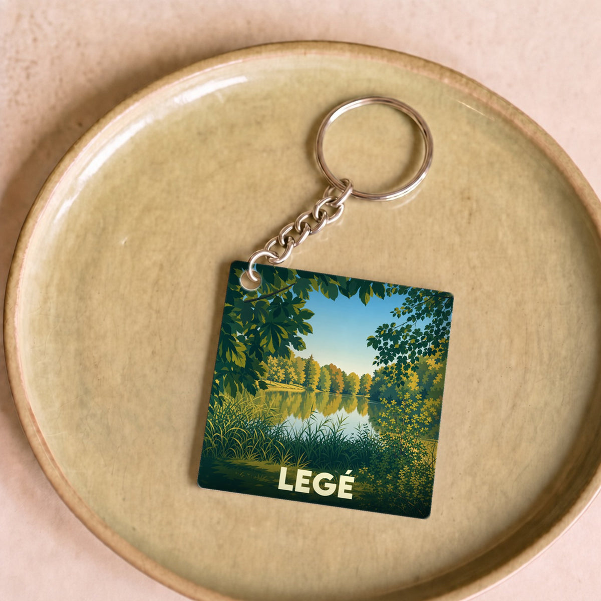 Porte-clés souvenir de la ville de Legé avec une illustration stylisée de paysage naturel.