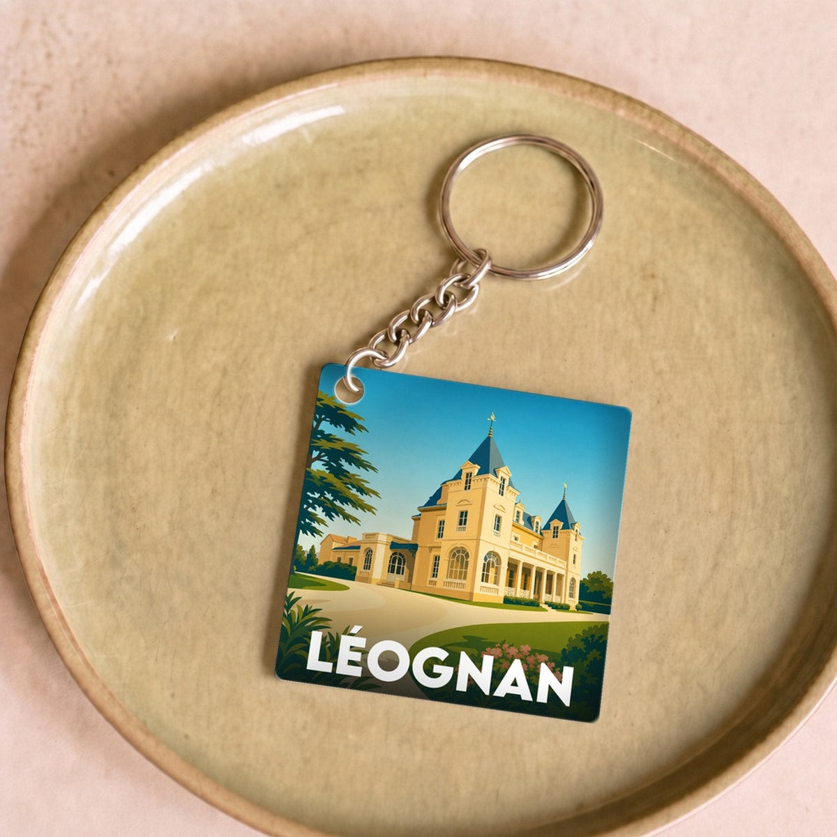 Porte-clés souvenir de la ville de Léognan avec une illustration stylisée.