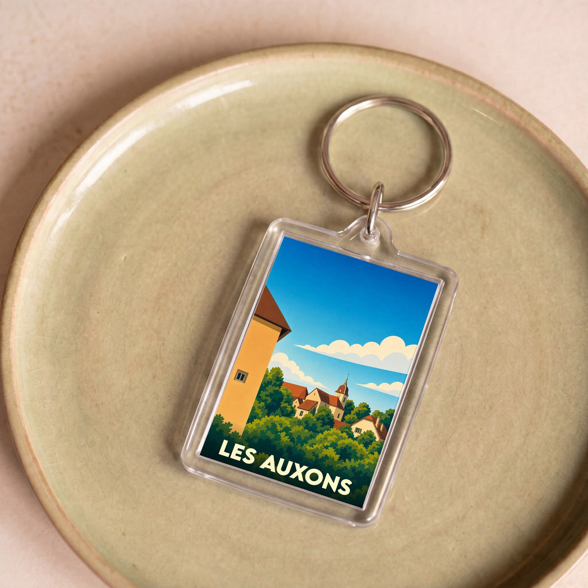 Porte-clés souvenir de la ville de Les Auxons avec une illustration stylisée.