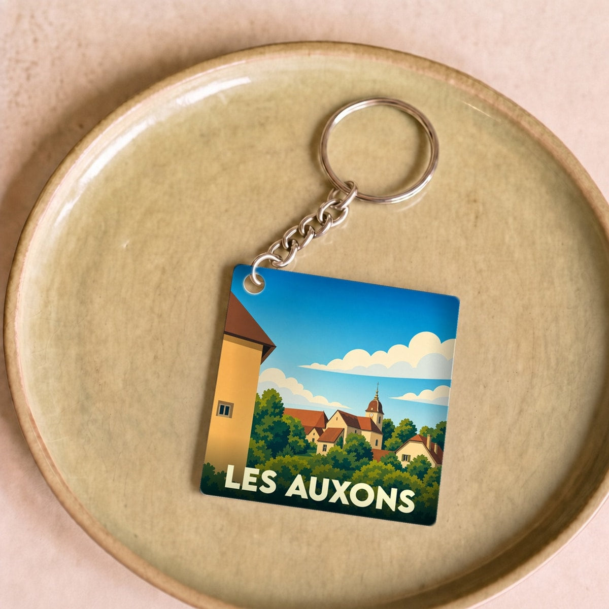 Porte-clés souvenir de la ville de Les Auxons avec une illustration stylisée.