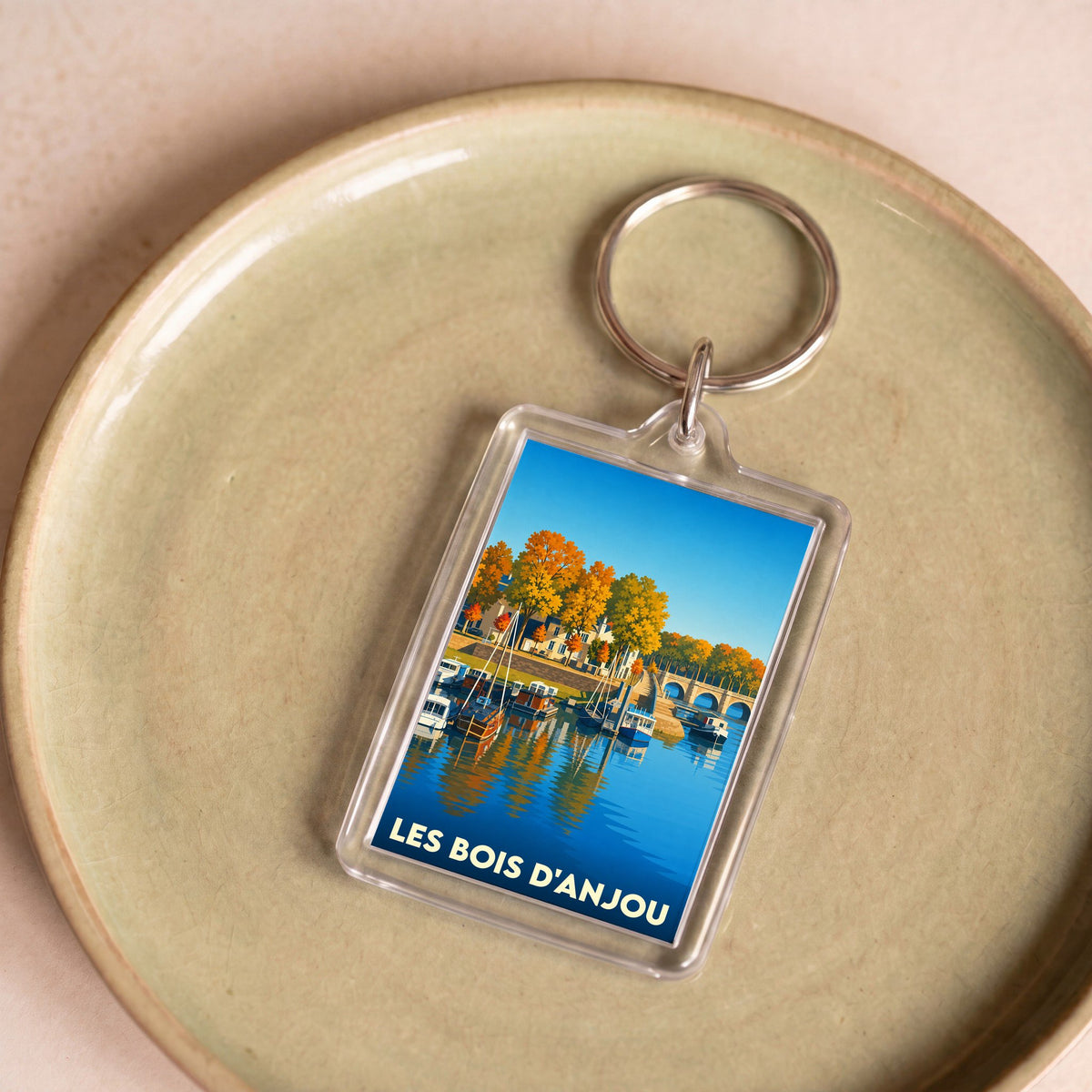 Porte-clés souvenir de la ville de Les Bois d'Anjou avec une illustration stylisée d'un port fluvial en automne.
