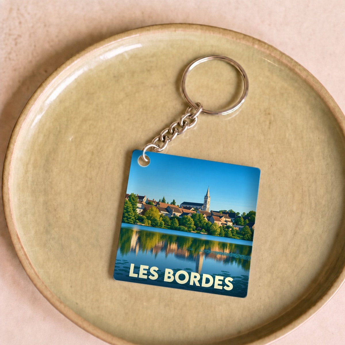 Porte-clés souvenir de la ville de Les Bordes avec une illustration stylisée d'un paysage au bord de l'eau.