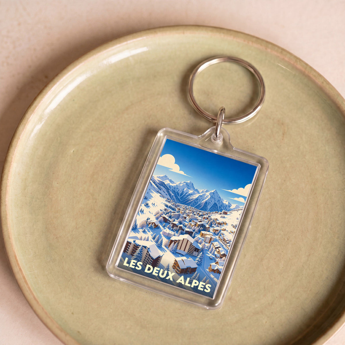 Porte-clés souvenir de la ville des Deux Alpes avec une illustration stylisée d'une station de ski enneigée.