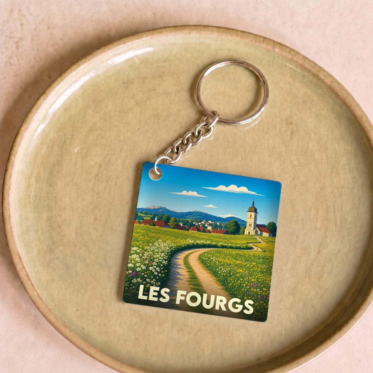 Porte-clés souvenir de la ville de Les Fourgs avec une illustration stylisée d'un paysage de campagne.