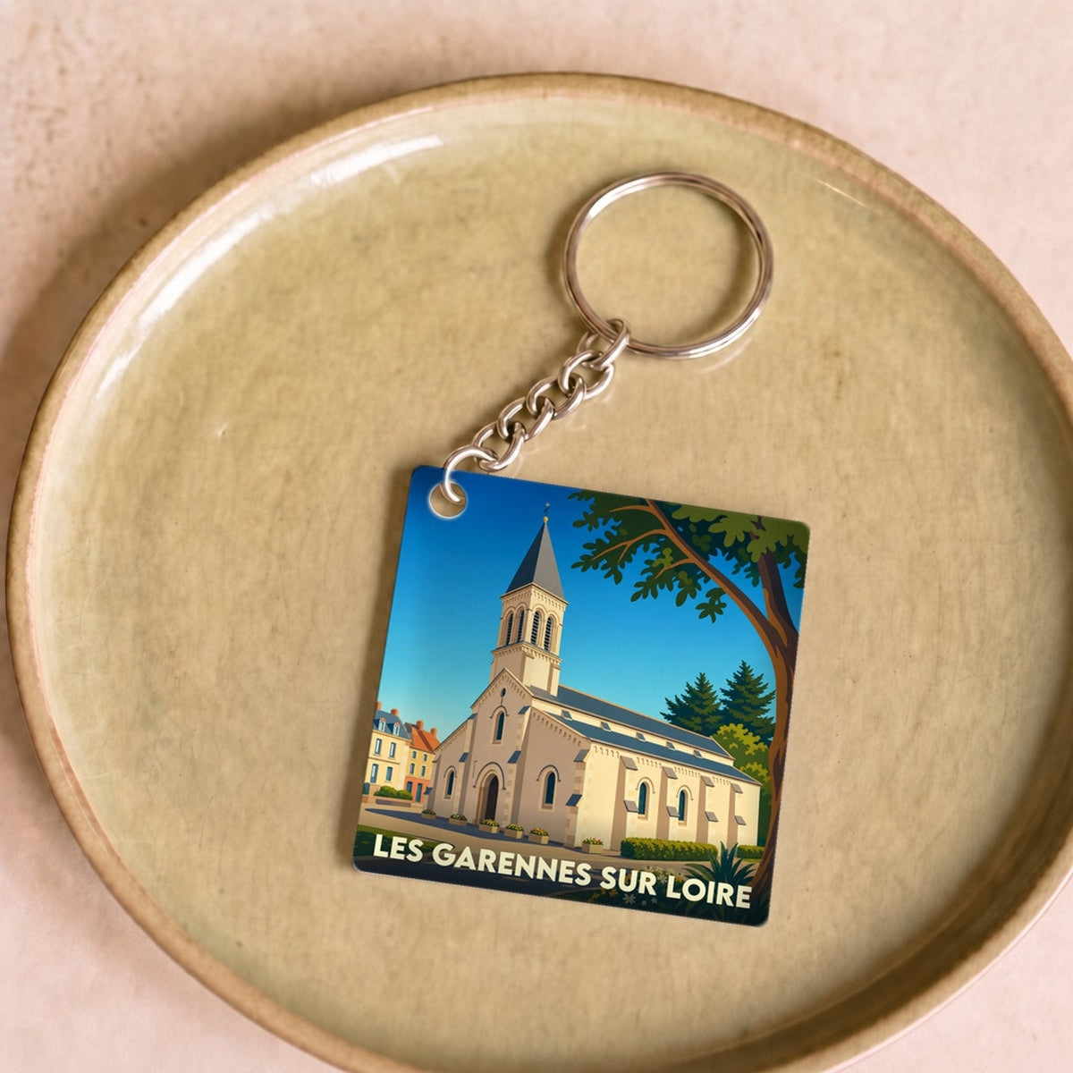 Porte-clés souvenir de la ville de Les Garennes sur Loire avec une illustration stylisée de son église.
