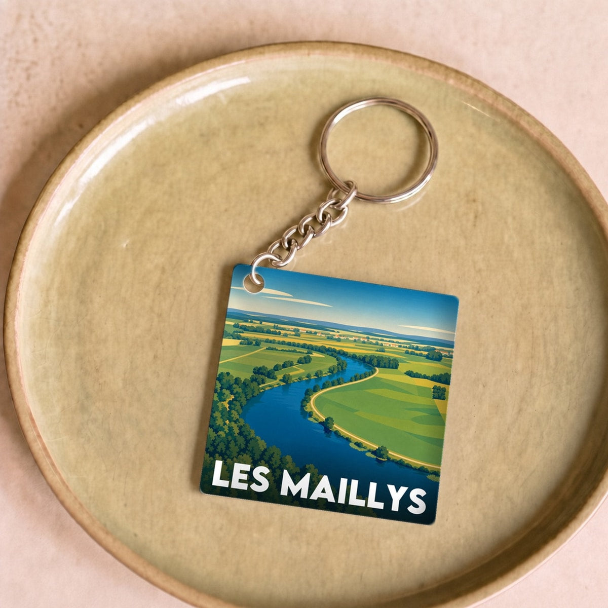 Porte-clés souvenir de la ville de Les Maillys avec une illustration stylisée d'un paysage.