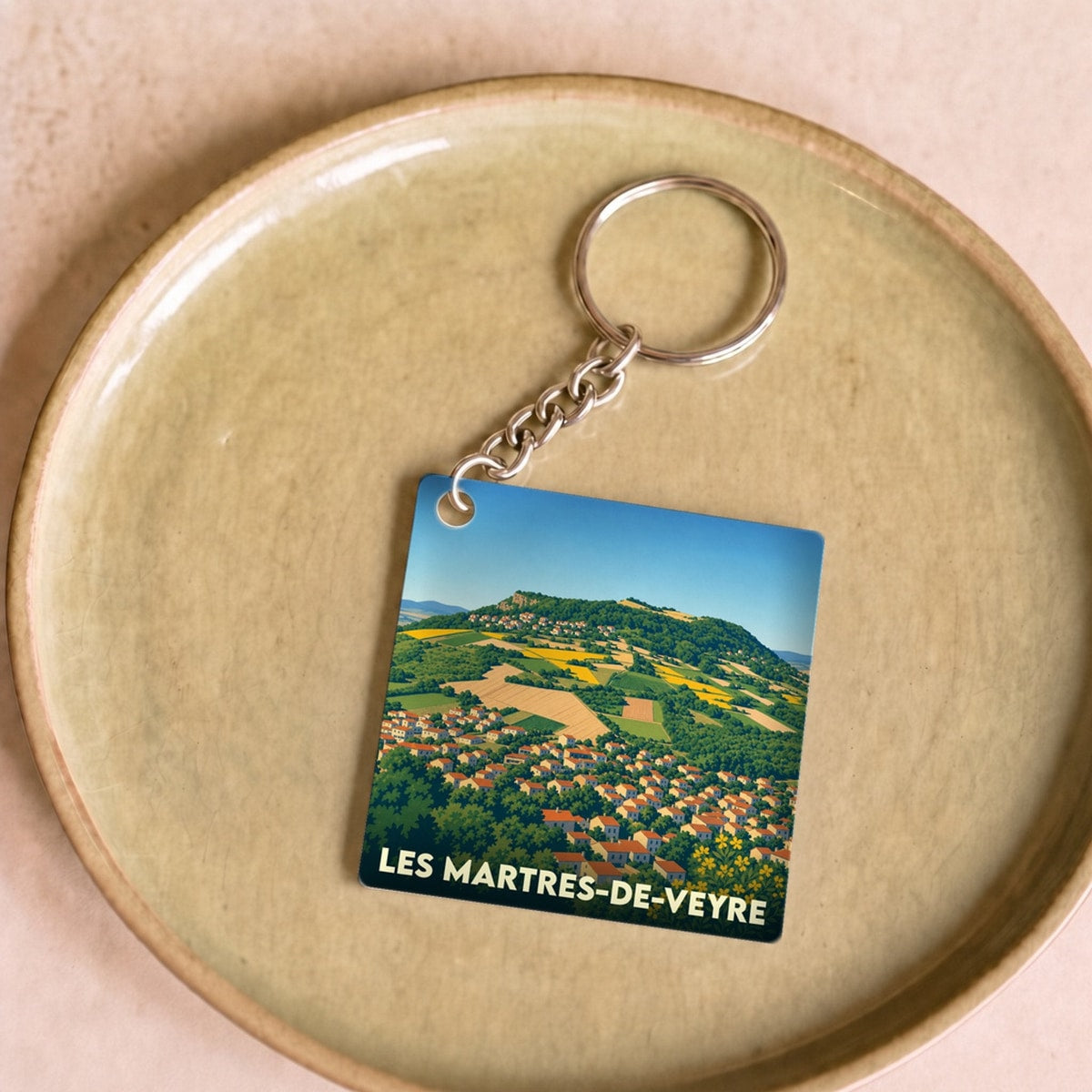 Porte-clés souvenir de la ville de Les Martres-de-Veyre avec une illustration stylisée du paysage local.