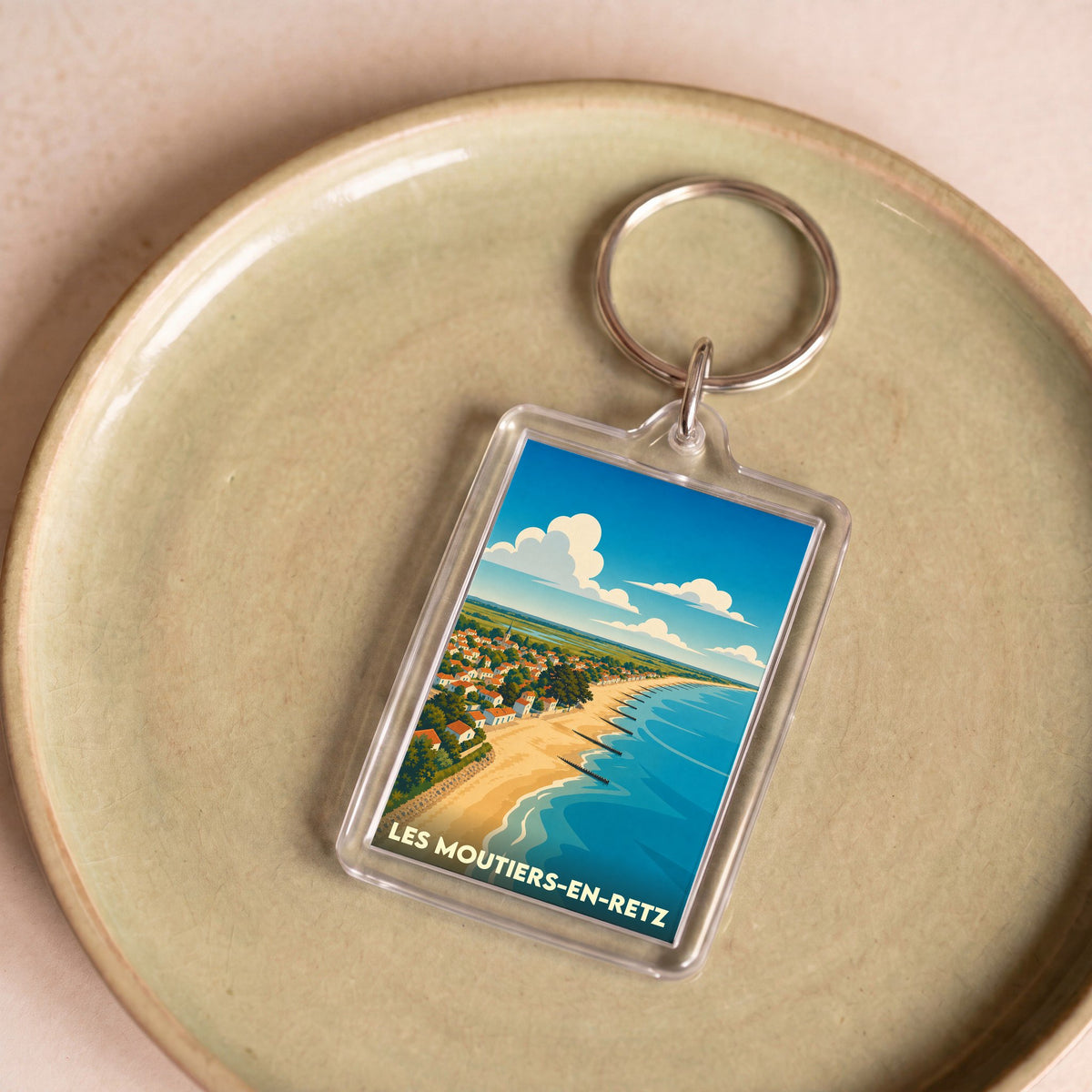 Porte-clés souvenir de la ville de Les Moutiers-en-Retz avec une illustration stylisée de la plage et du littoral.