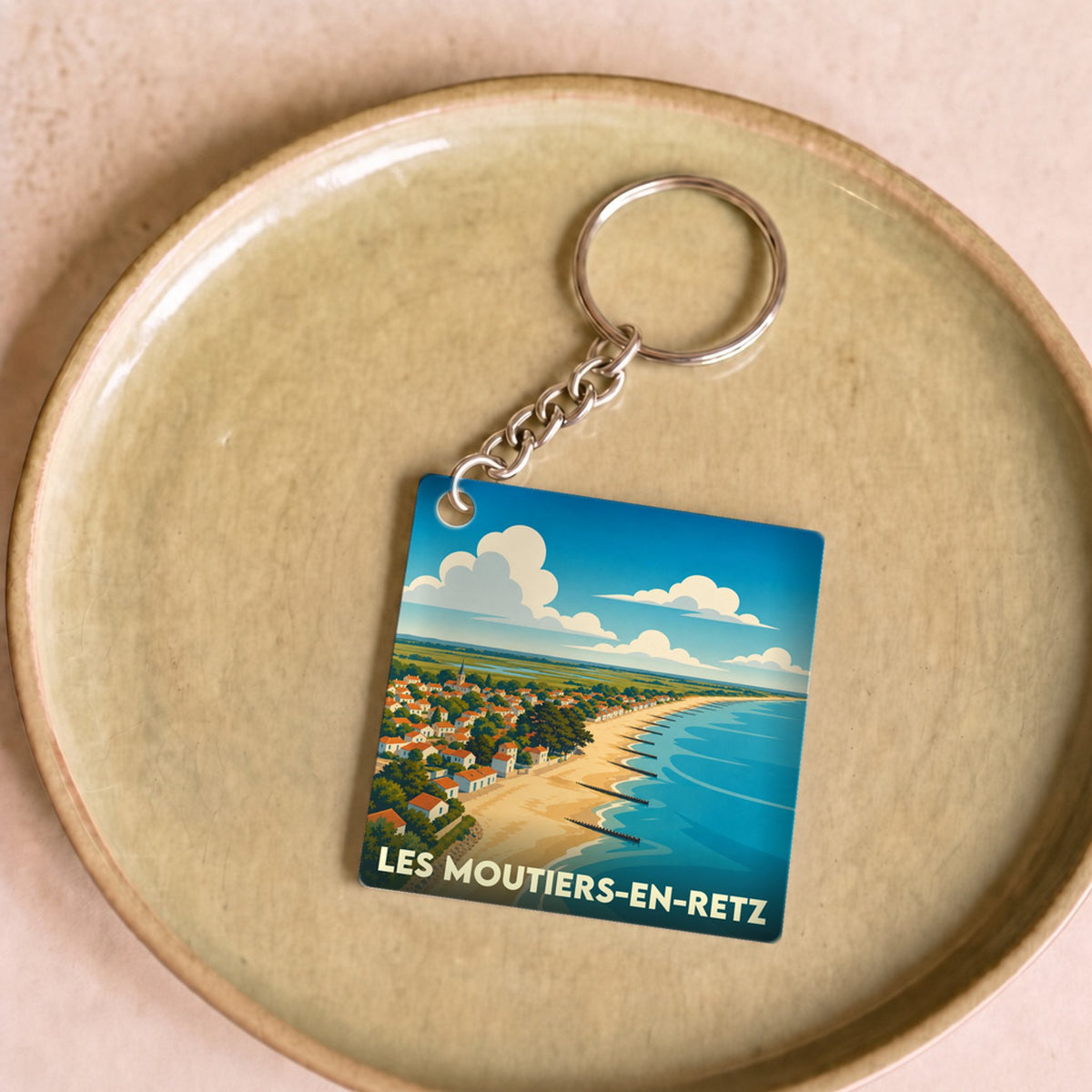 Porte-clés souvenir de la ville de Les Moutiers-en-Retz avec une illustration stylisée de la plage et du littoral.