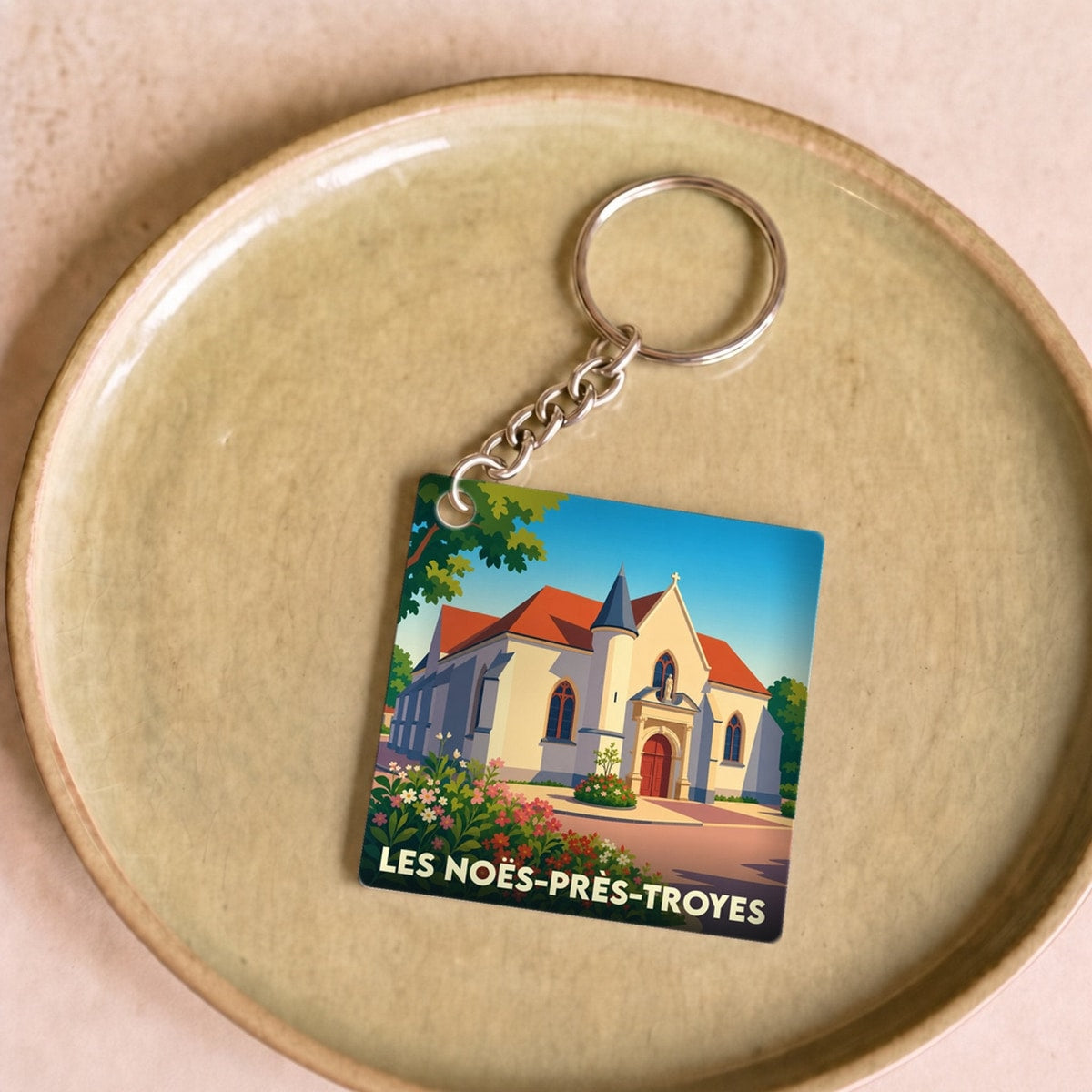 Porte-clés souvenir de la ville de Les Noës-près-Troyes avec une illustration stylisée d'une église.